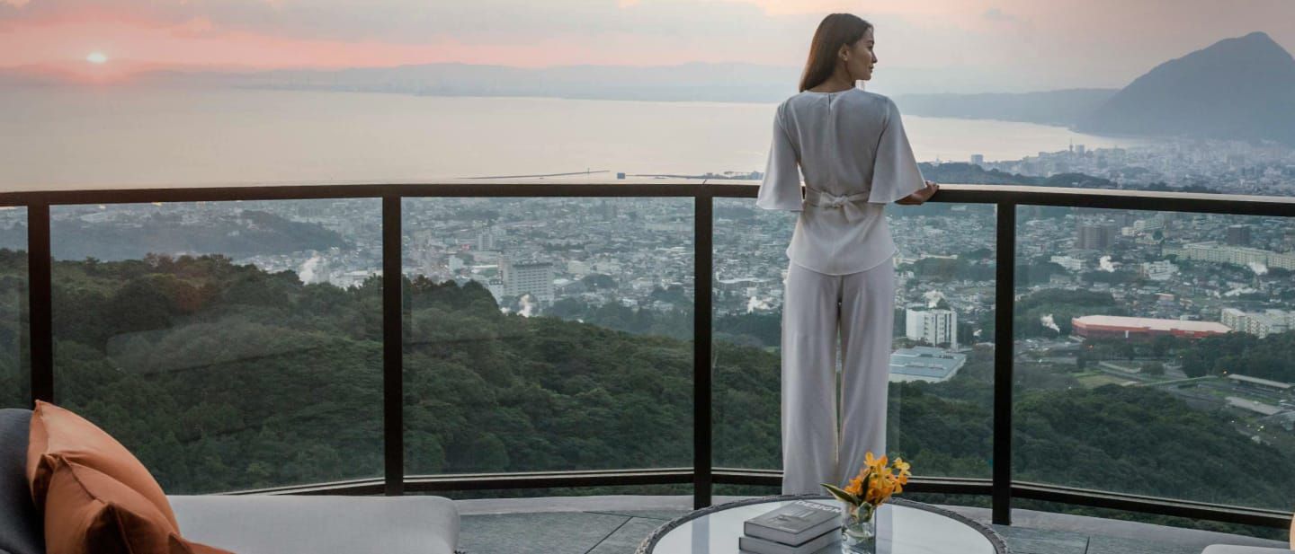 Woman gazing from hotel balcony overlooking the city & waterscapes