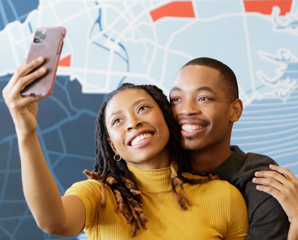 Couple taking pictures in front of colorful map at a Holiday Inn Express