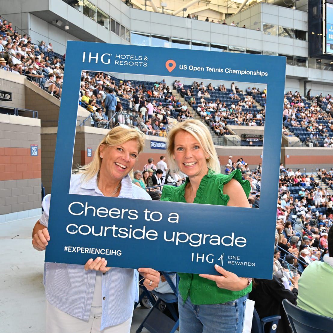 Two  winners of a courtside upgrade posing withtheir congratulatory sign