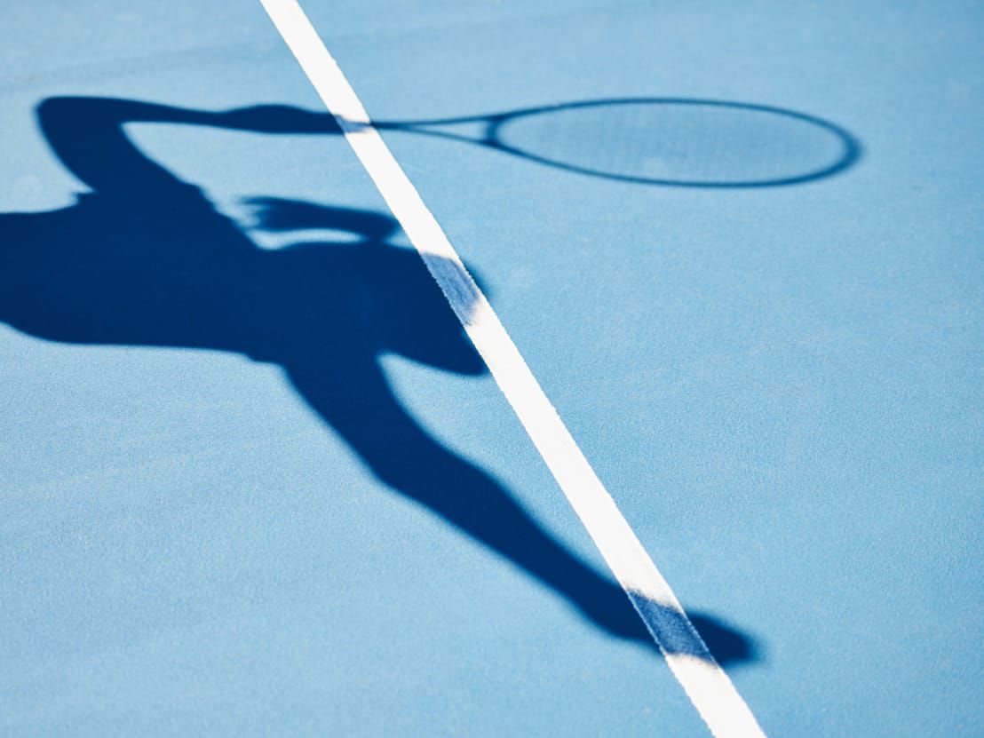 Shadow of a tennis player serving.