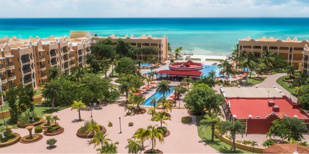 Resort frente al mar con piscinas, paisajismo tropical y senderos que conducen a la playa.