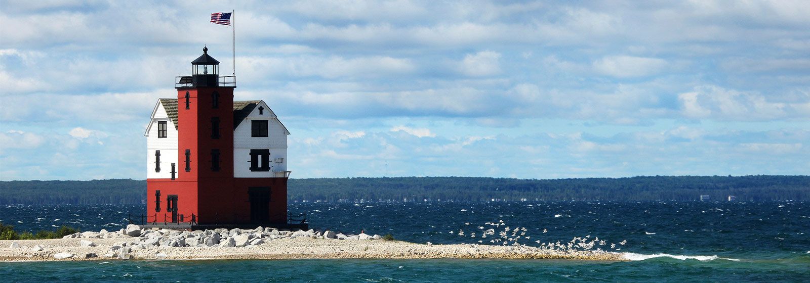 Red and white lighthouse on rocky flat shore