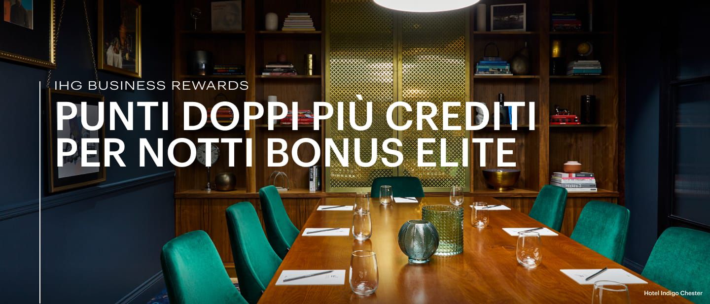 Una tavola con bicchieri e sedie verdi in una sala riunioni e uno spazio per eventi con una libreria all'Hotel Indigo Chester