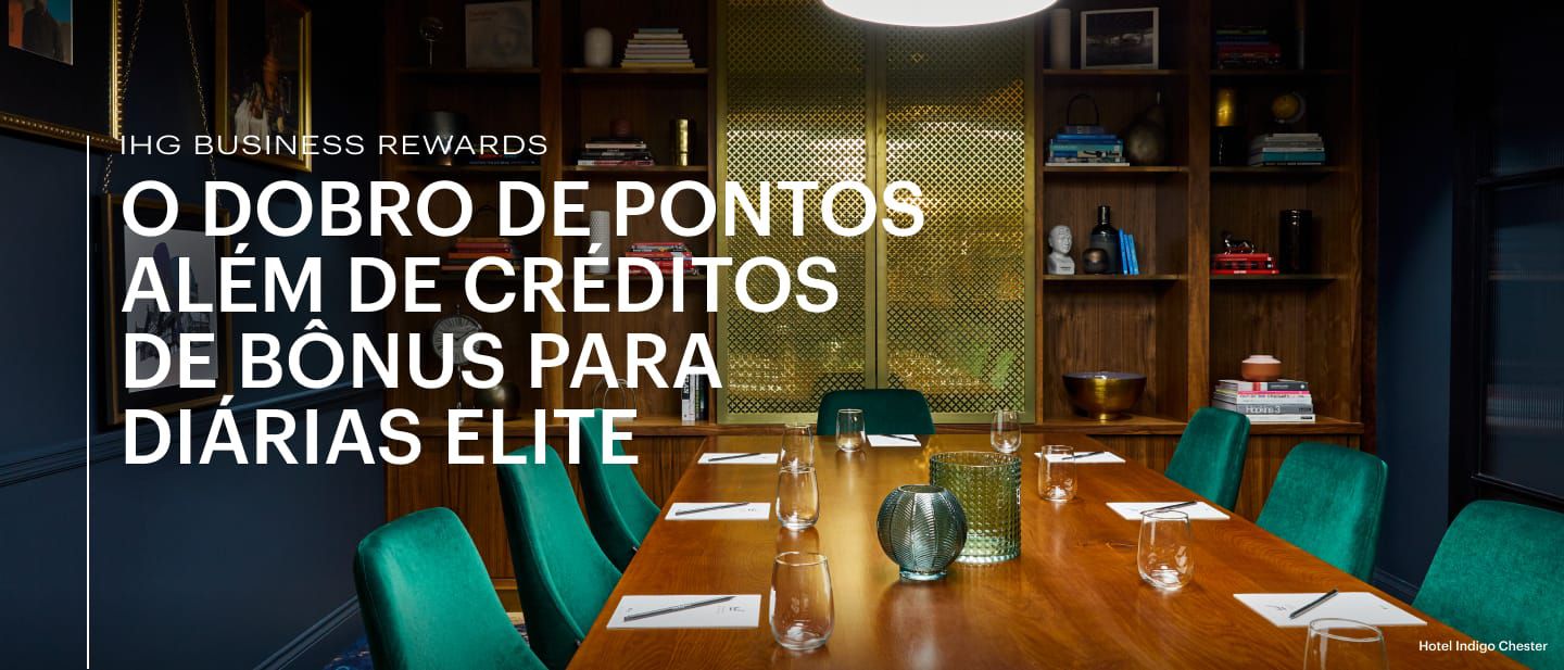 Uma mesa com copos e cadeiras verdes em uma sala de reuniões e eventos com uma estante no Hotel Indigo Chester