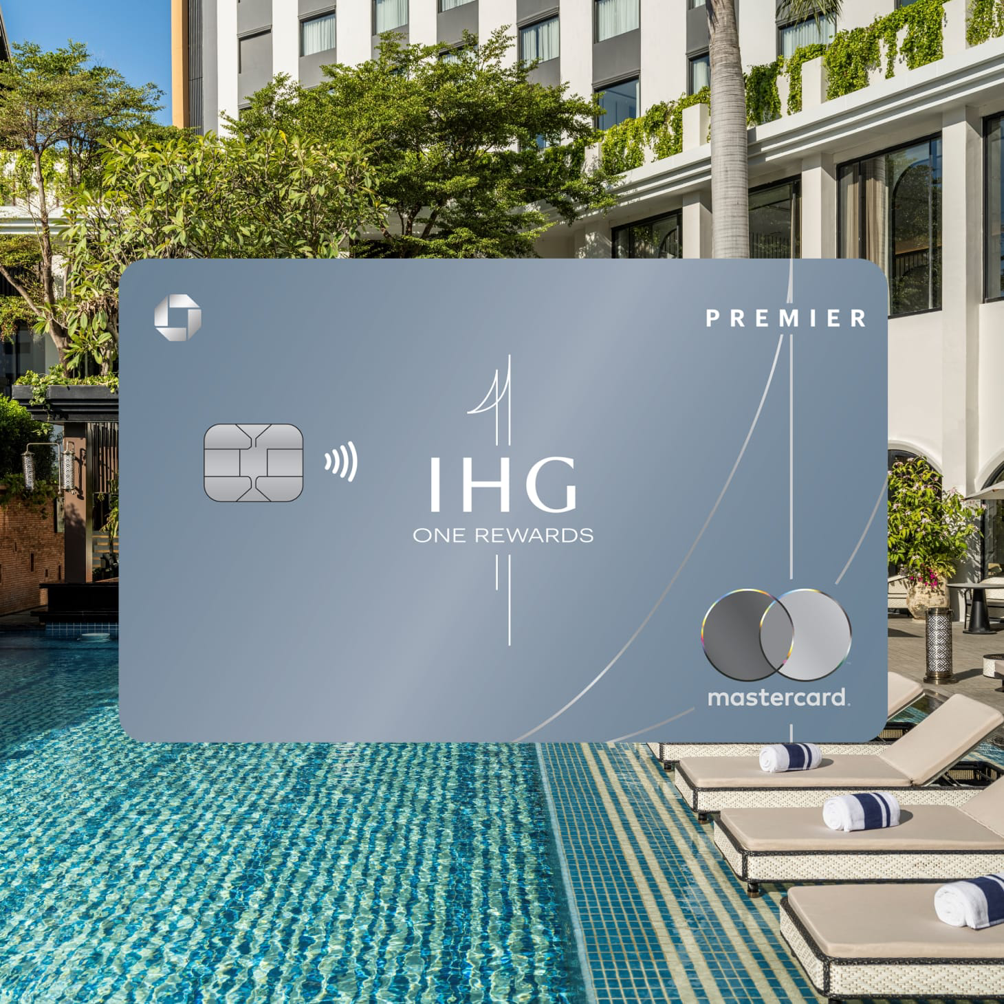 IHG One Rewards Premier Credit Card overlaid on scene of pool flanked by loungers