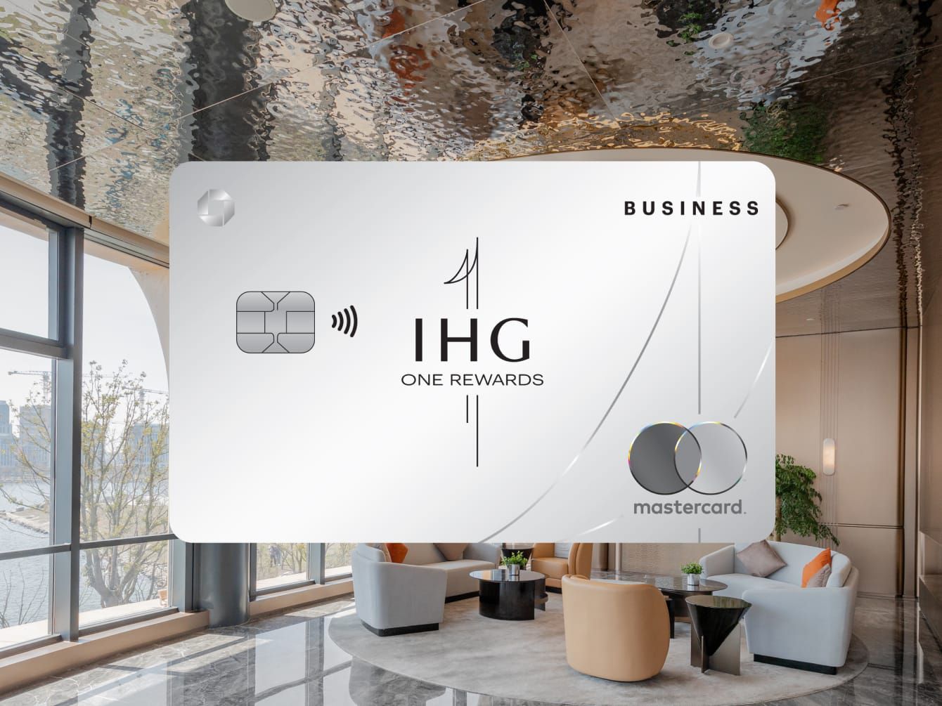 IHG One Rewards Business Credit Card overlaid on lobby scene with a dramatic chandelier.