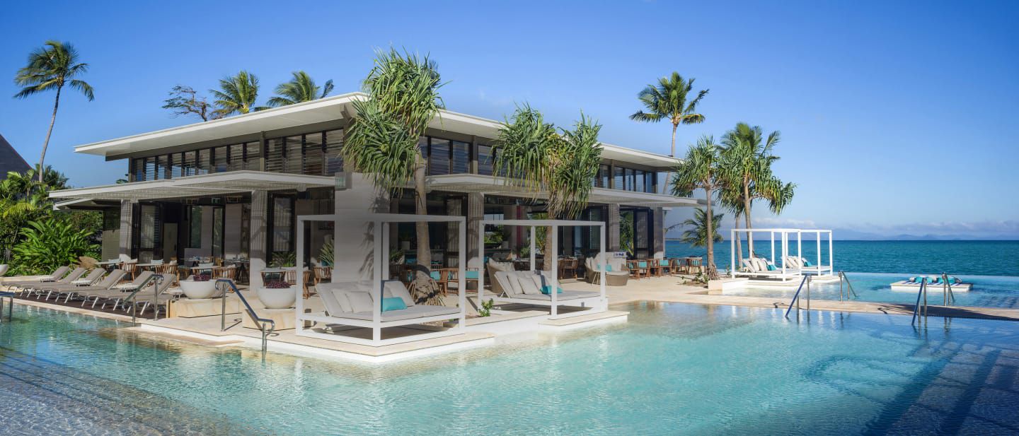 Beachfront resort with palm trees and poolside cabanas