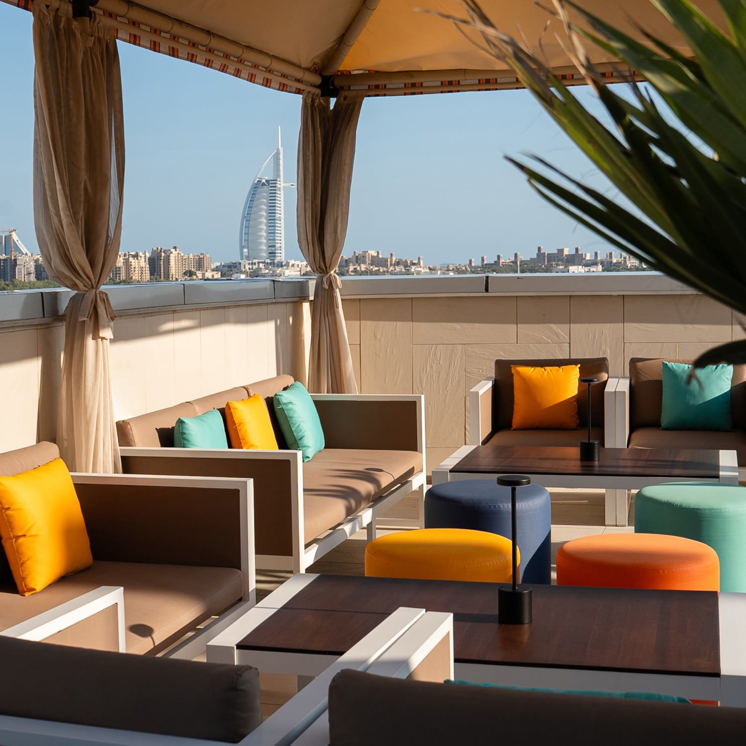 Under a cabana with lots of seating options accented with colorful pillows and a view toward the city skyline.