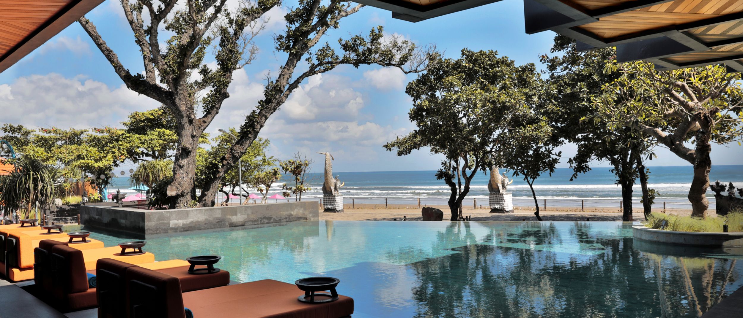 Visual of the beachfront infinity pool at Hotel Indigo Bali Seminyak Beach, with tropical trees and ocean in the background.