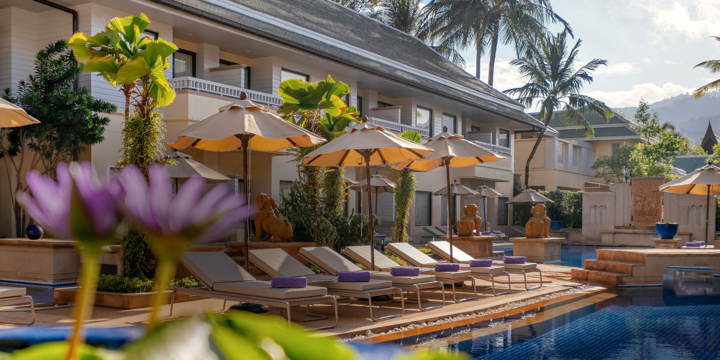 A poolside scene with sun loungers, umbrellas, and Holiday Inn Resort Phuket in the background.