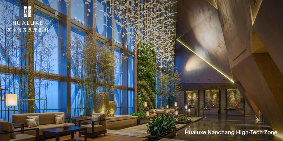 De lichte, open lobby van het Hualuxe Nanchang met indrukwekkend hoge plafonds, plantenbakken met bamboe en een kunstinstallatie met vogels van papier. 