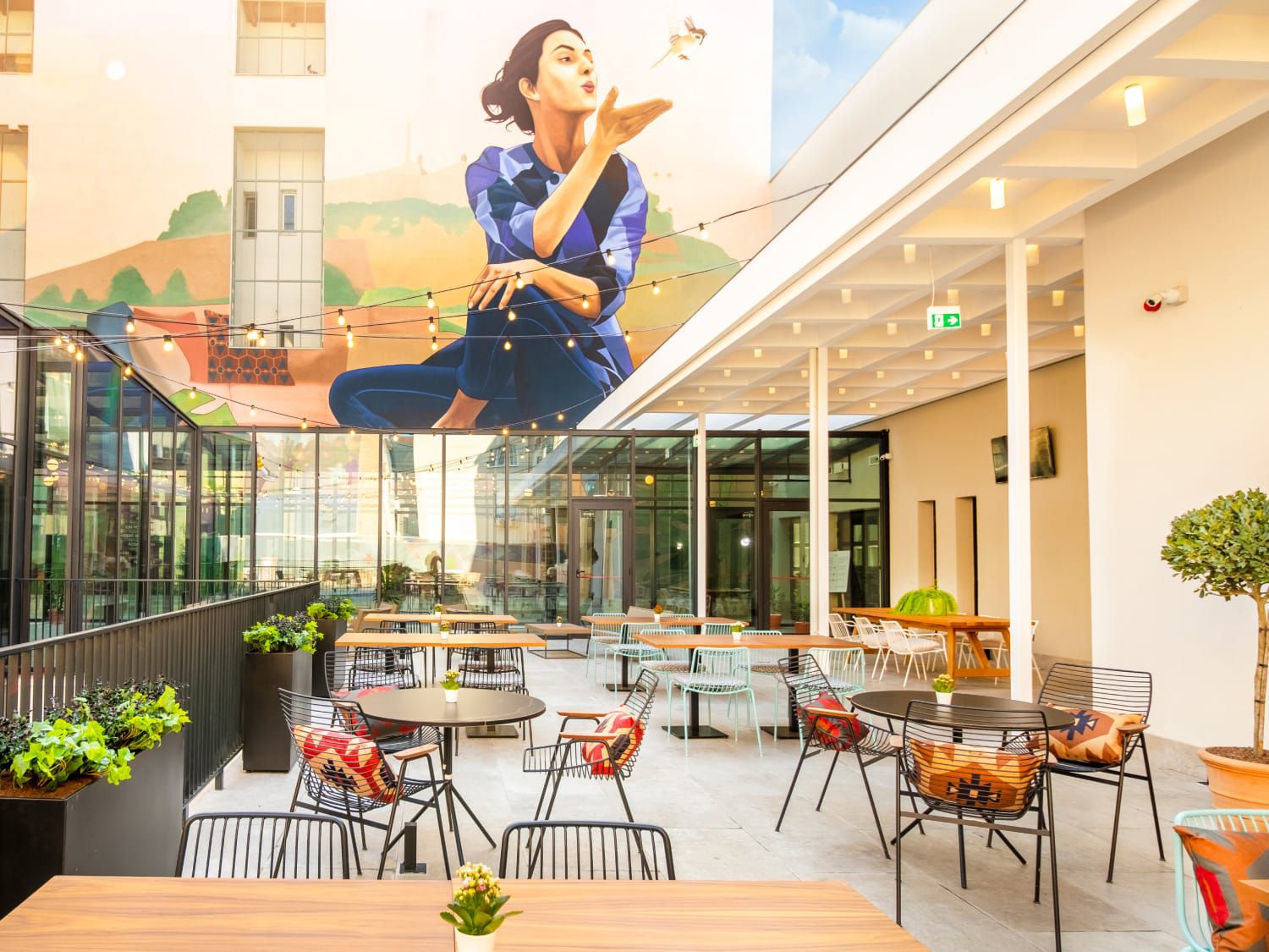 Outdoor seating area with mural of woman in nature