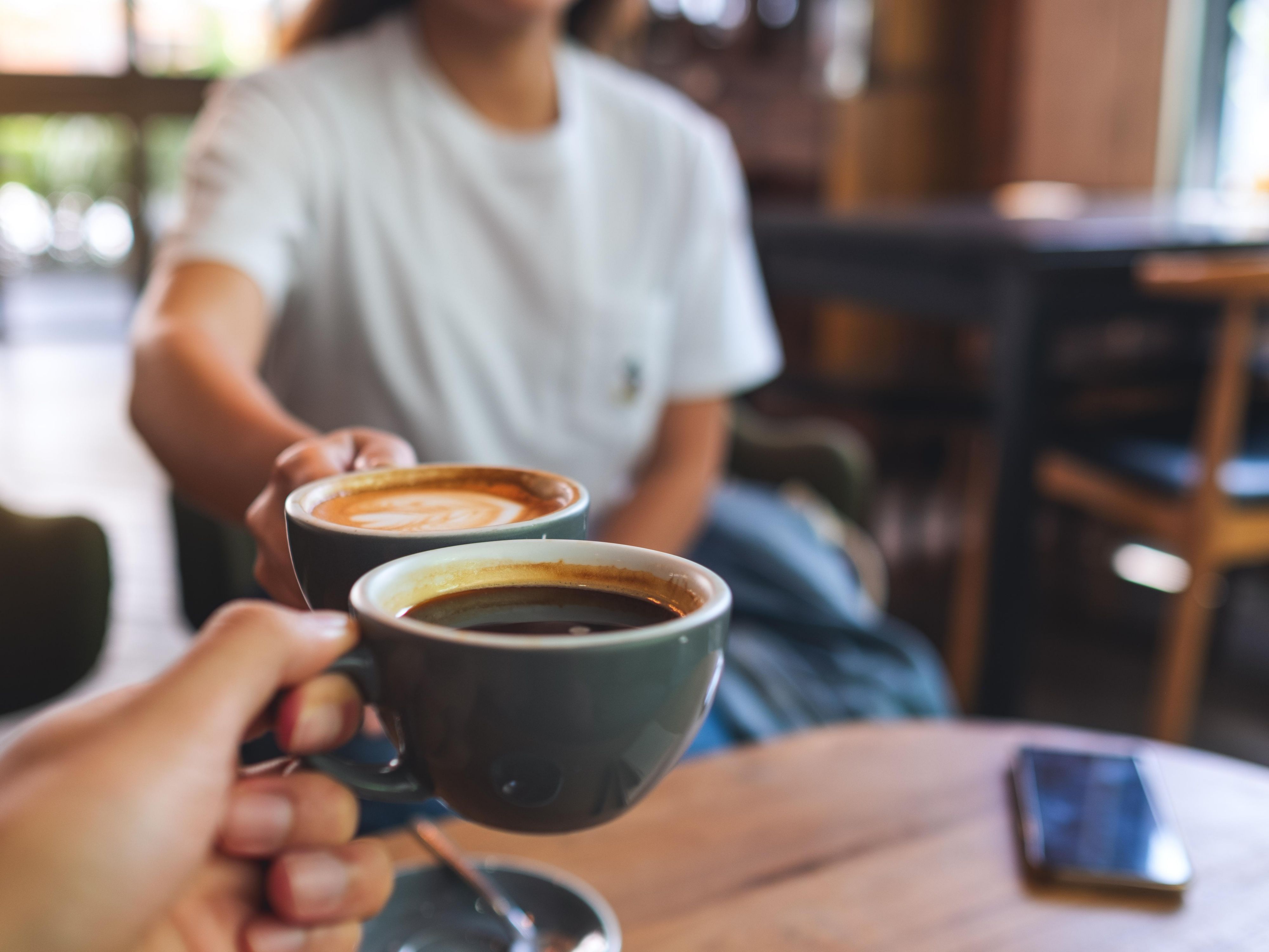 Two people drinking coffee from the free breakfast buffet.