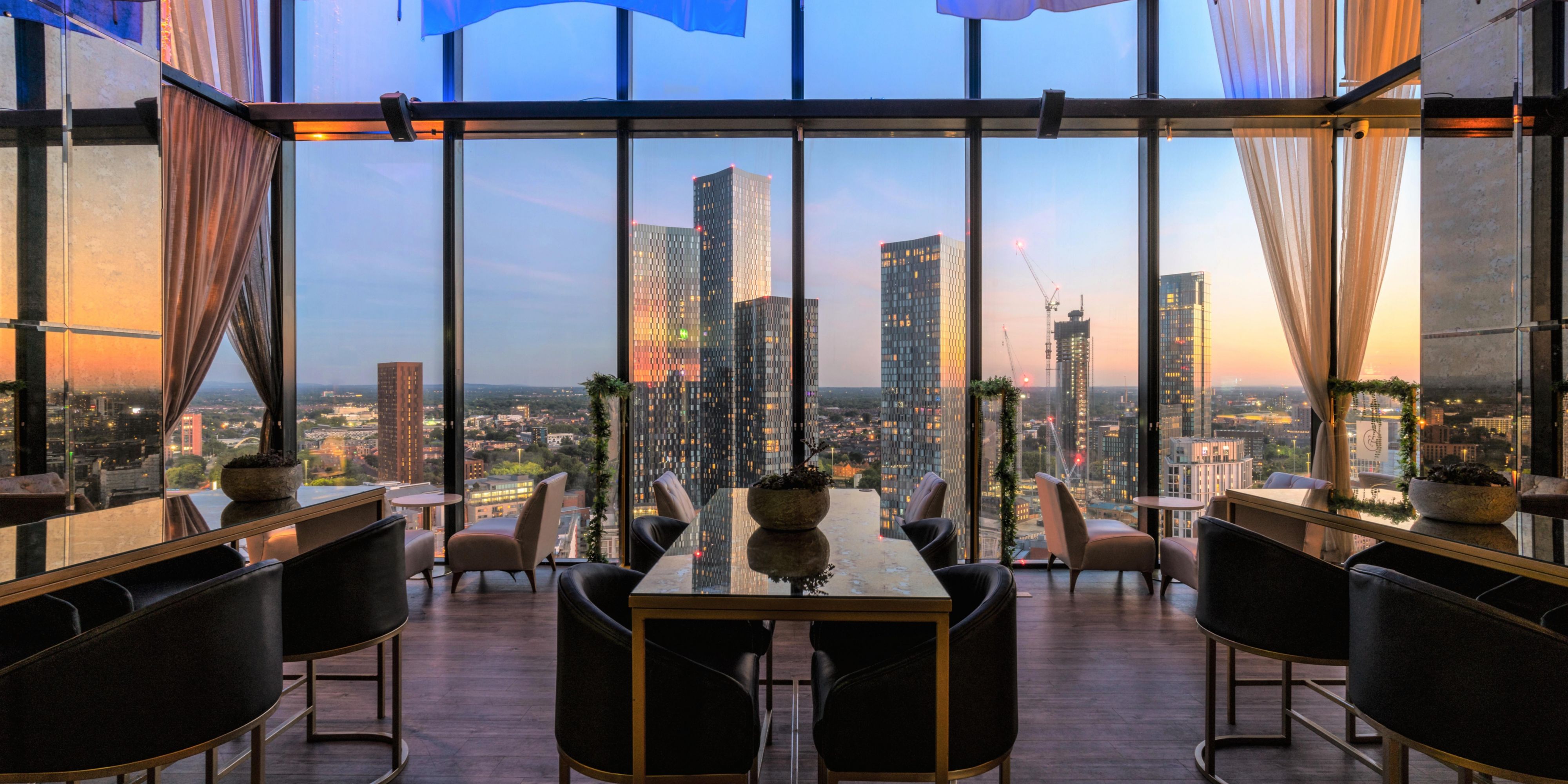 Bar seating area with skyline city views at sunset