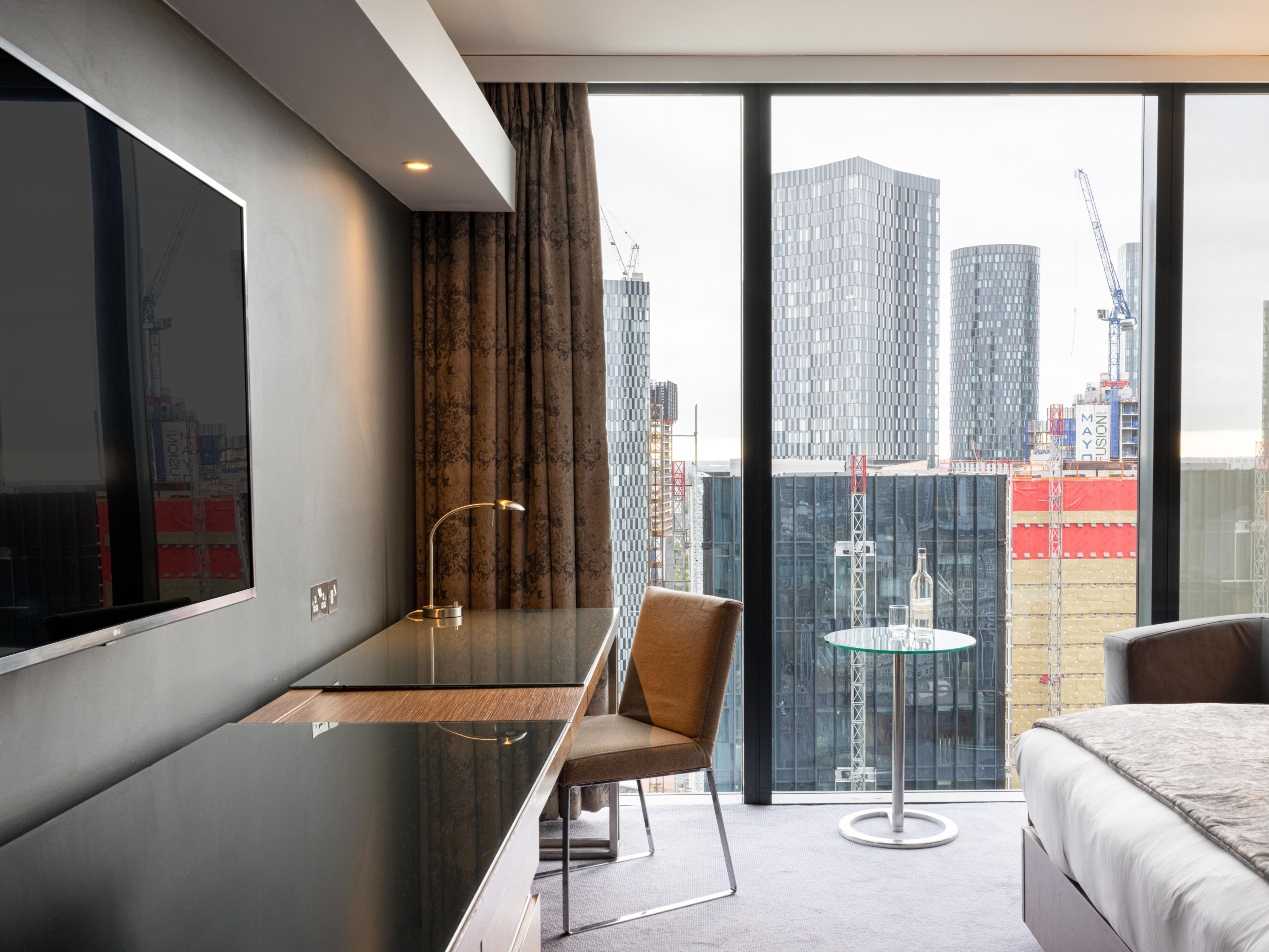 hotel guest suite with desk, tv, and city views