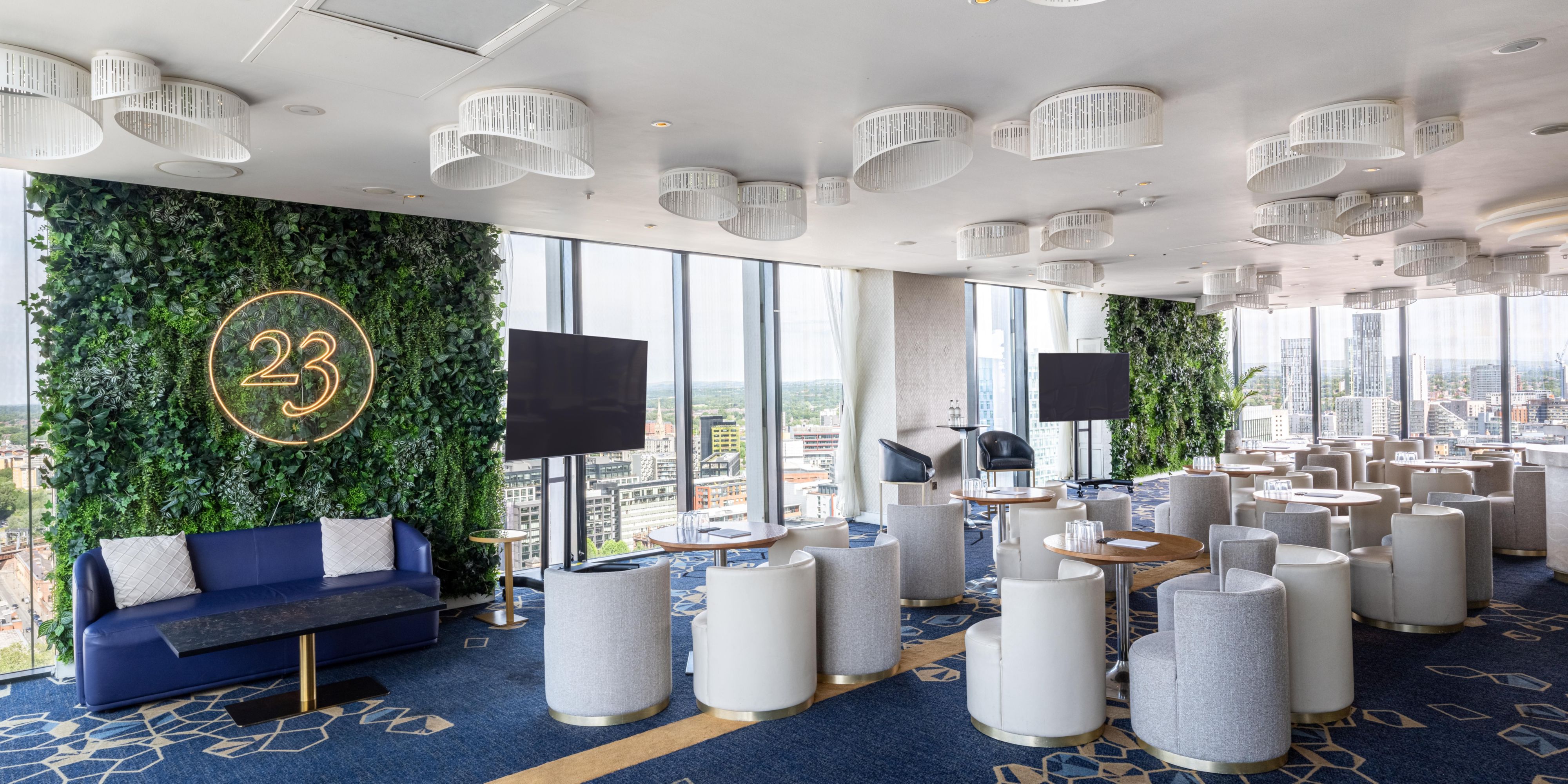 cloud23 seating area with tv's, cosy armchairs, and panormaic views of the city