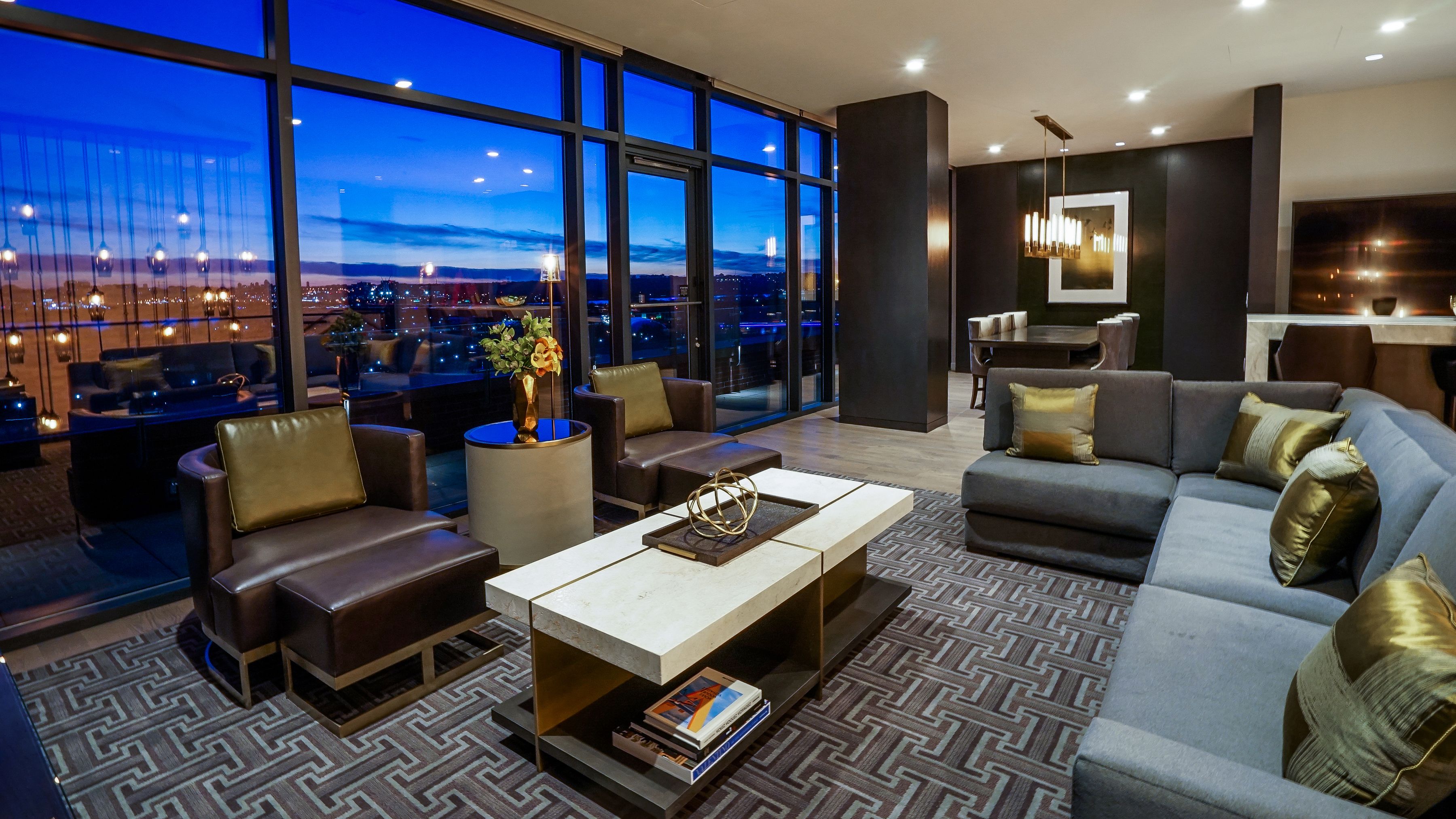 Sophisticated lounge with floor-to-ceiling windows, contemporary seating, and panoramic evening views of Washington, D.C.