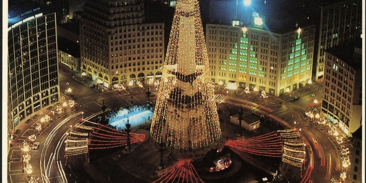 Monument Circle glows with festive holiday lights and a towering illuminated display in the heart of downtown Indianapolis at night.