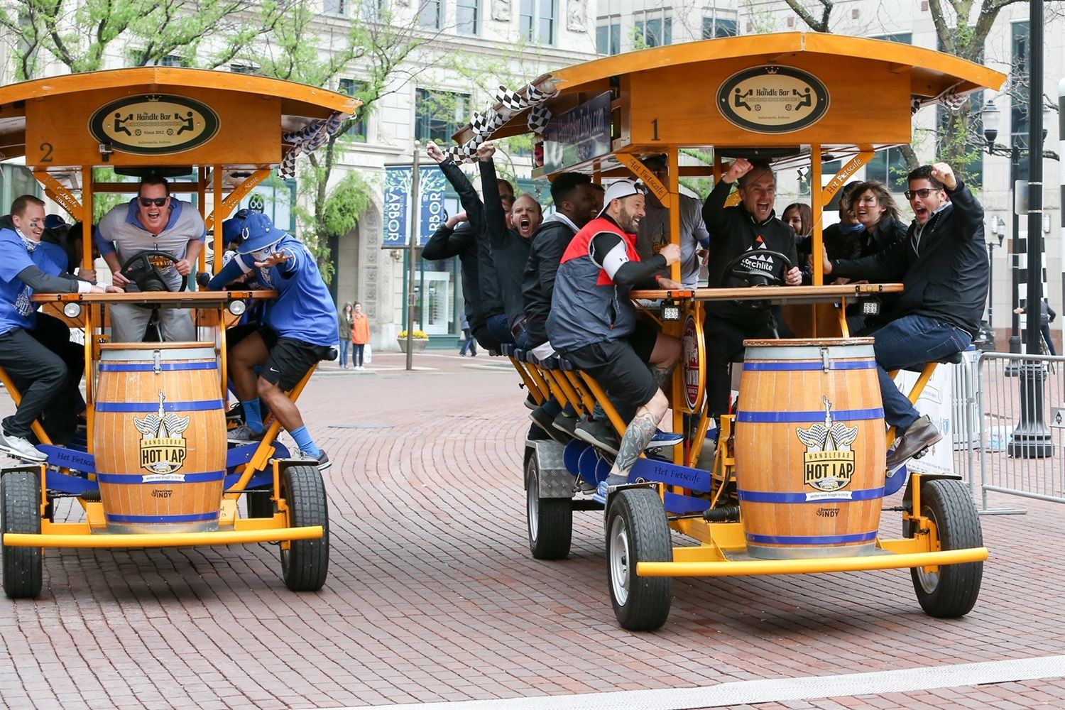Participants ride a HandleBar pedal pub through downtown Indianapolis, celebrating along a lively city street.