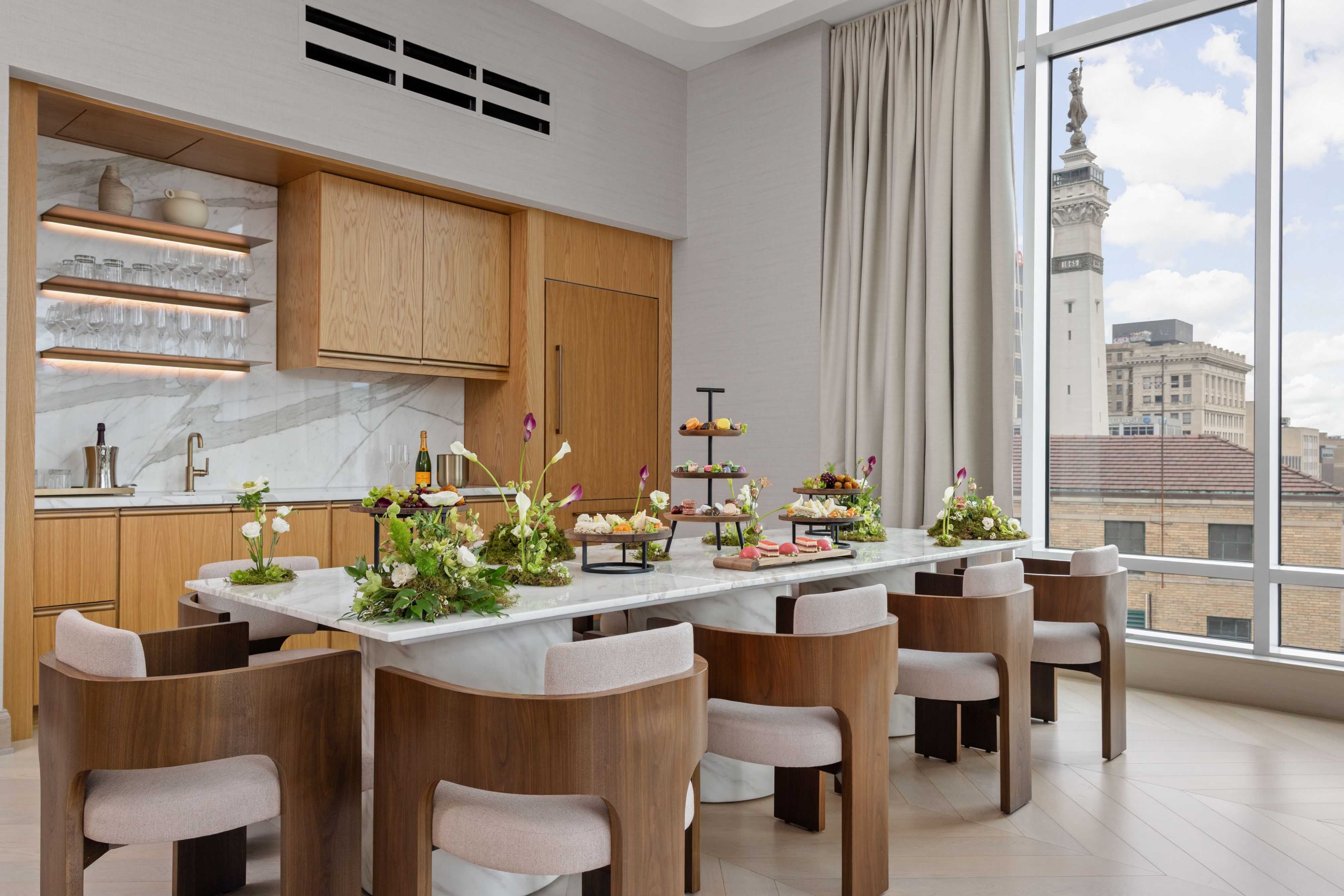 The Penthouse at InterContinental Indianapolis features a marble dining table with catered bites, and floor-to-ceiling windows.