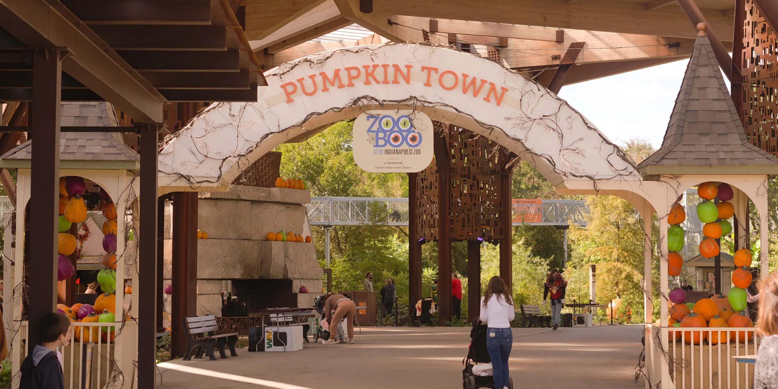 Families stroll through Pumpkin Town during ZooBoo at the Indianapolis Zoo, surrounded by seasonal decorations and autumn colors.