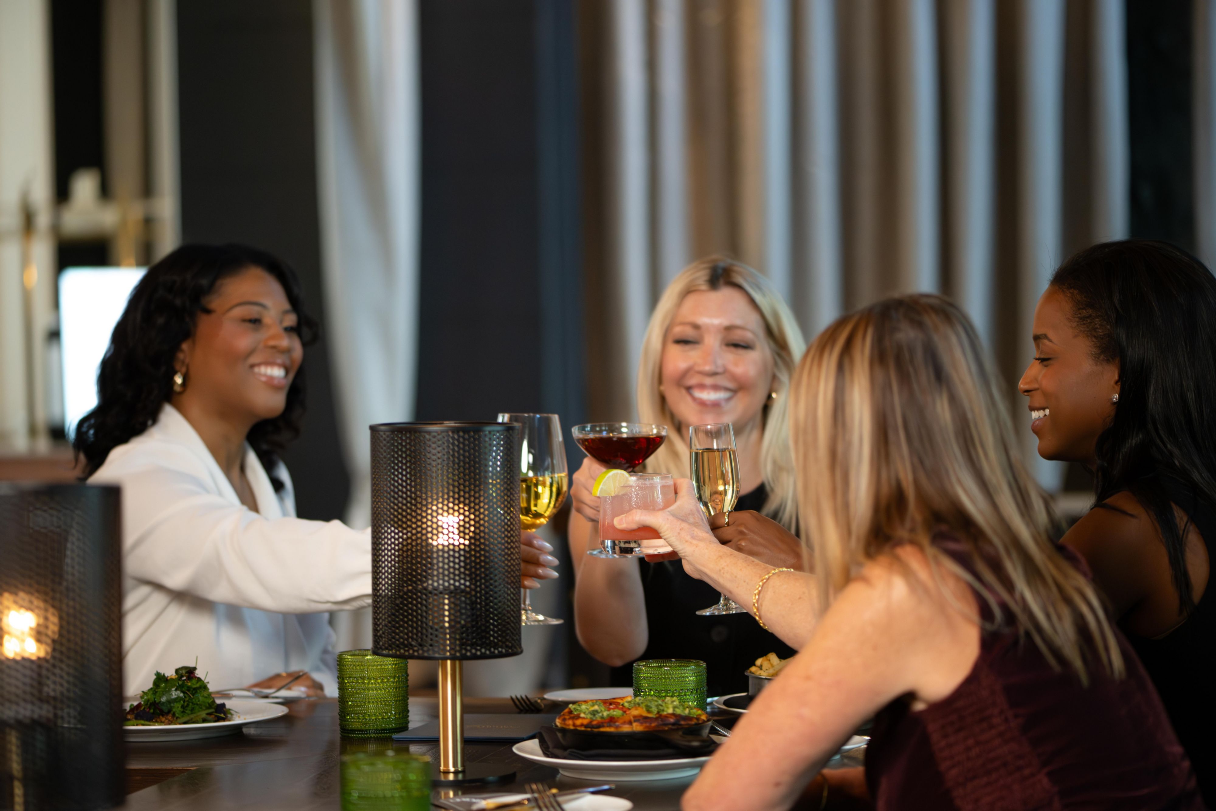 group of women making a toast with various cocktails