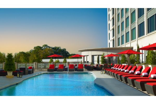 Outdoor pool with red lounge chairs and hotel terrace seating.
