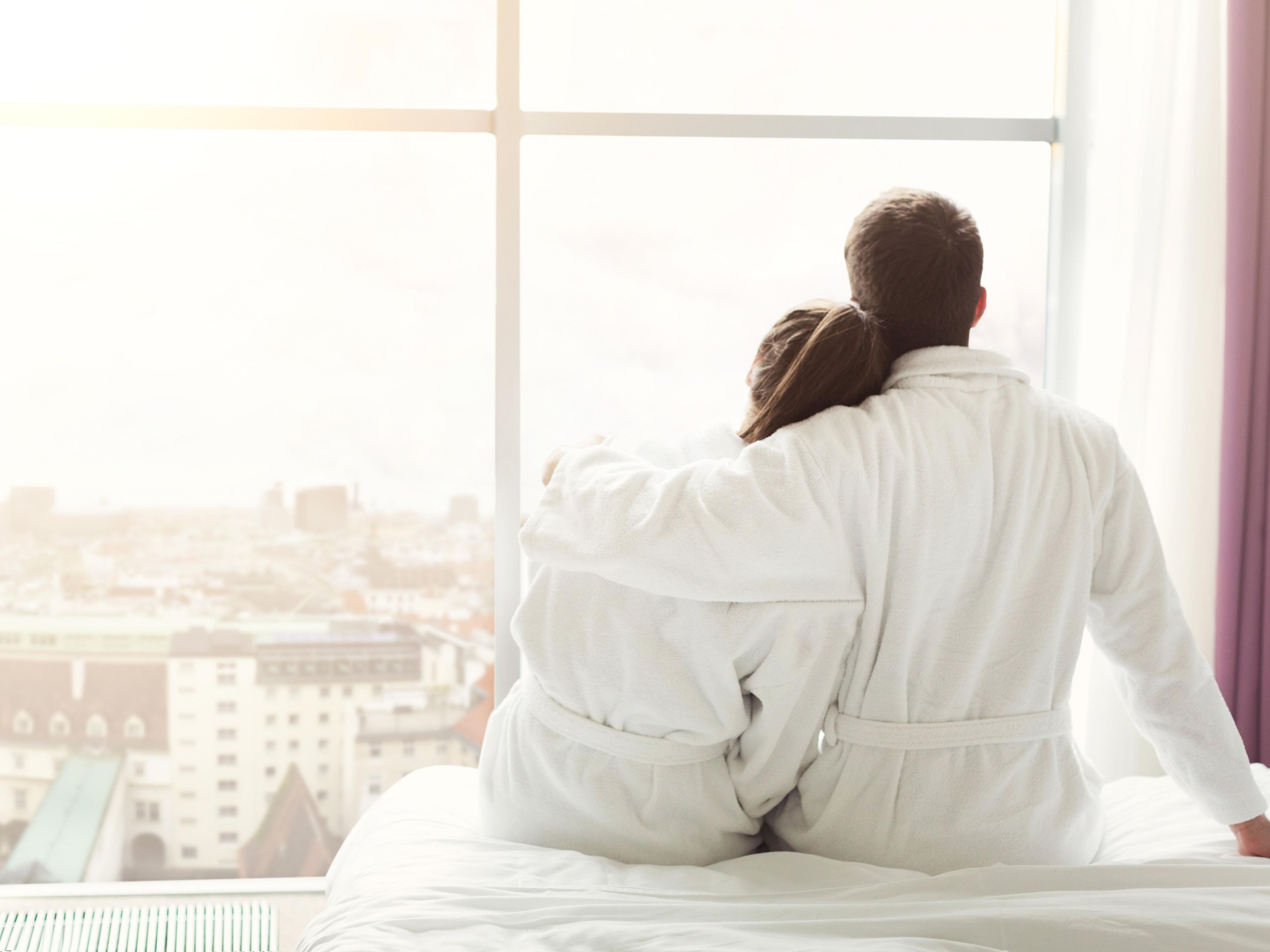 Couple sitting on hotel bed in robes
