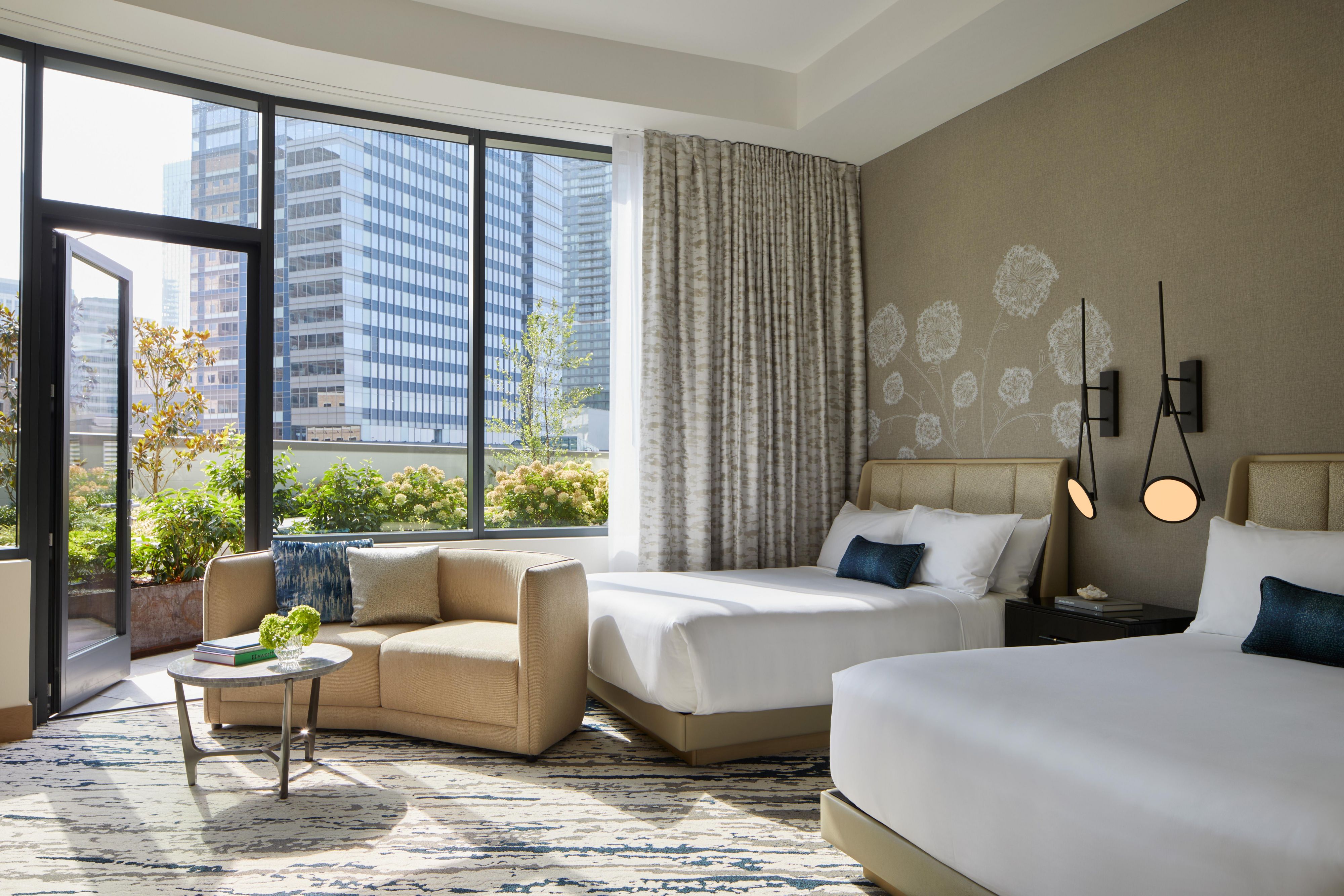 2 Queen Premium hotel room with couch seating and a door open to the balcony.