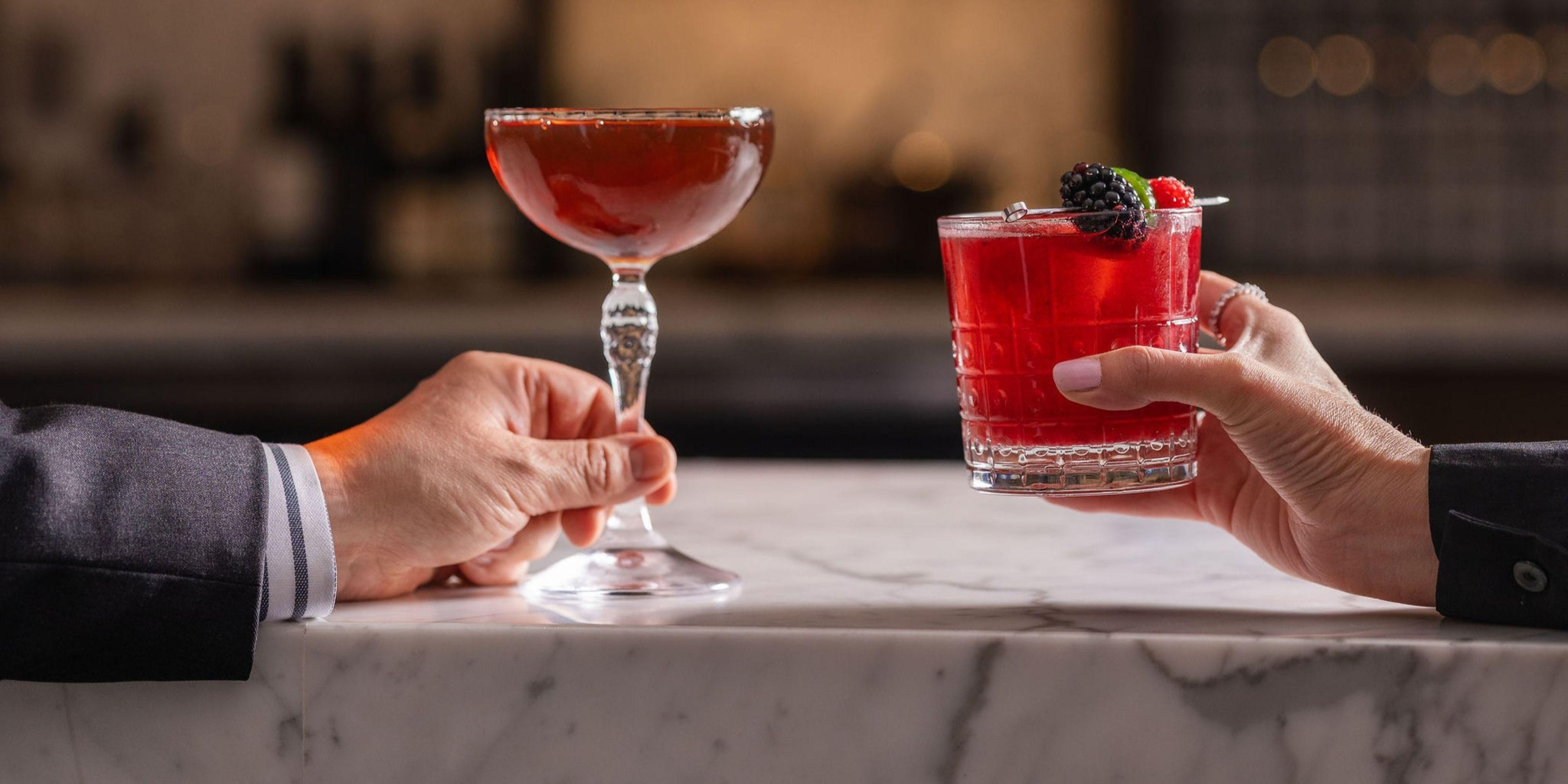 Close up of two guests' hands holding cocktails.