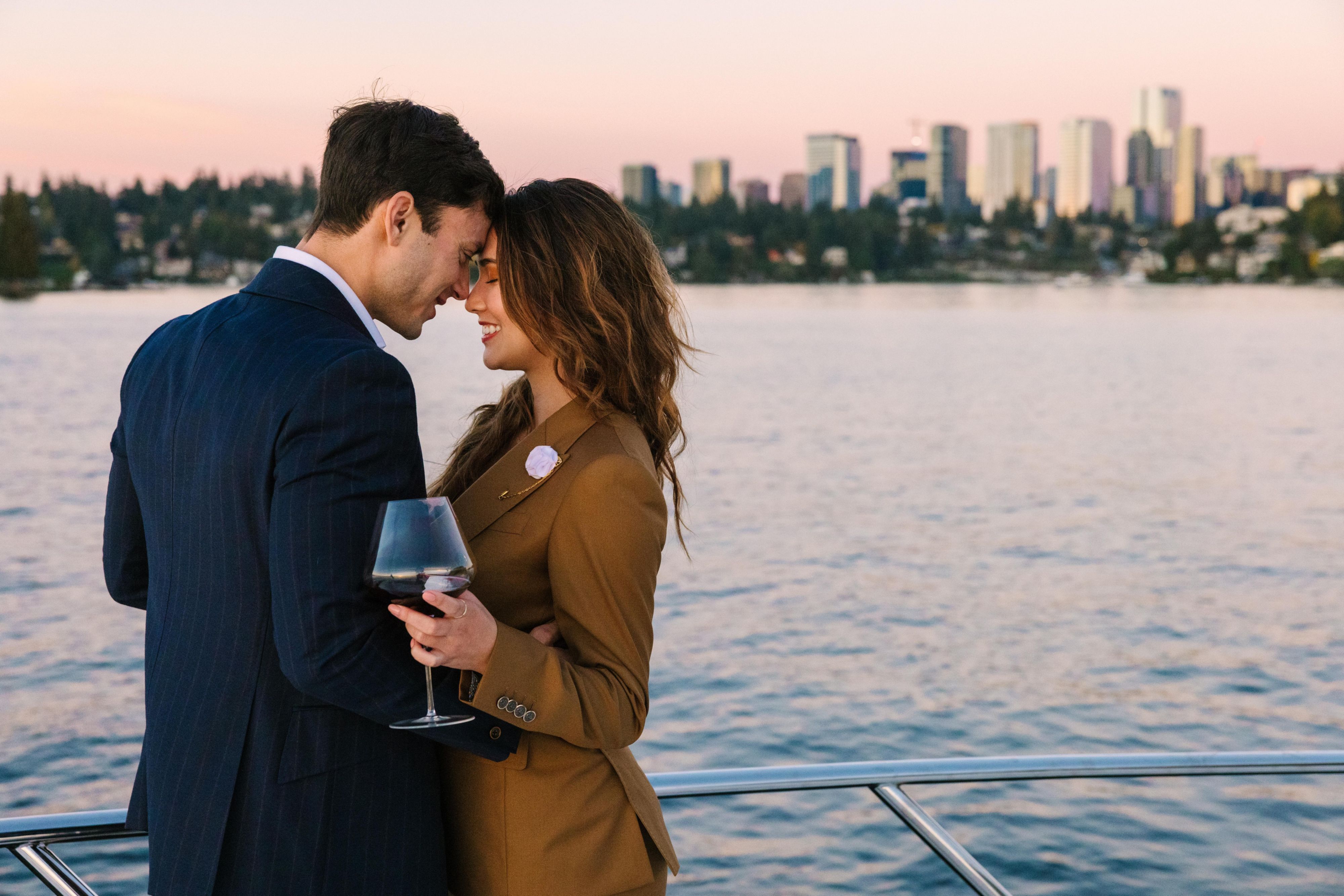 Couple embracing in front of the water across from the city skyline.