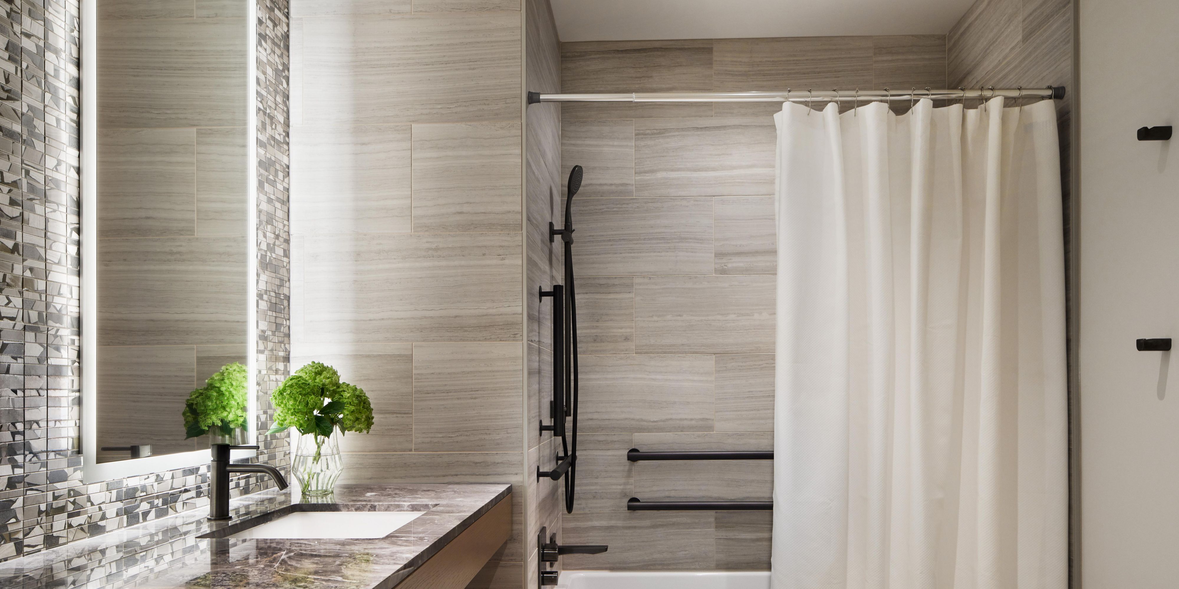 Refined ADA bathroom with tub, grab bars, & handheld shower head