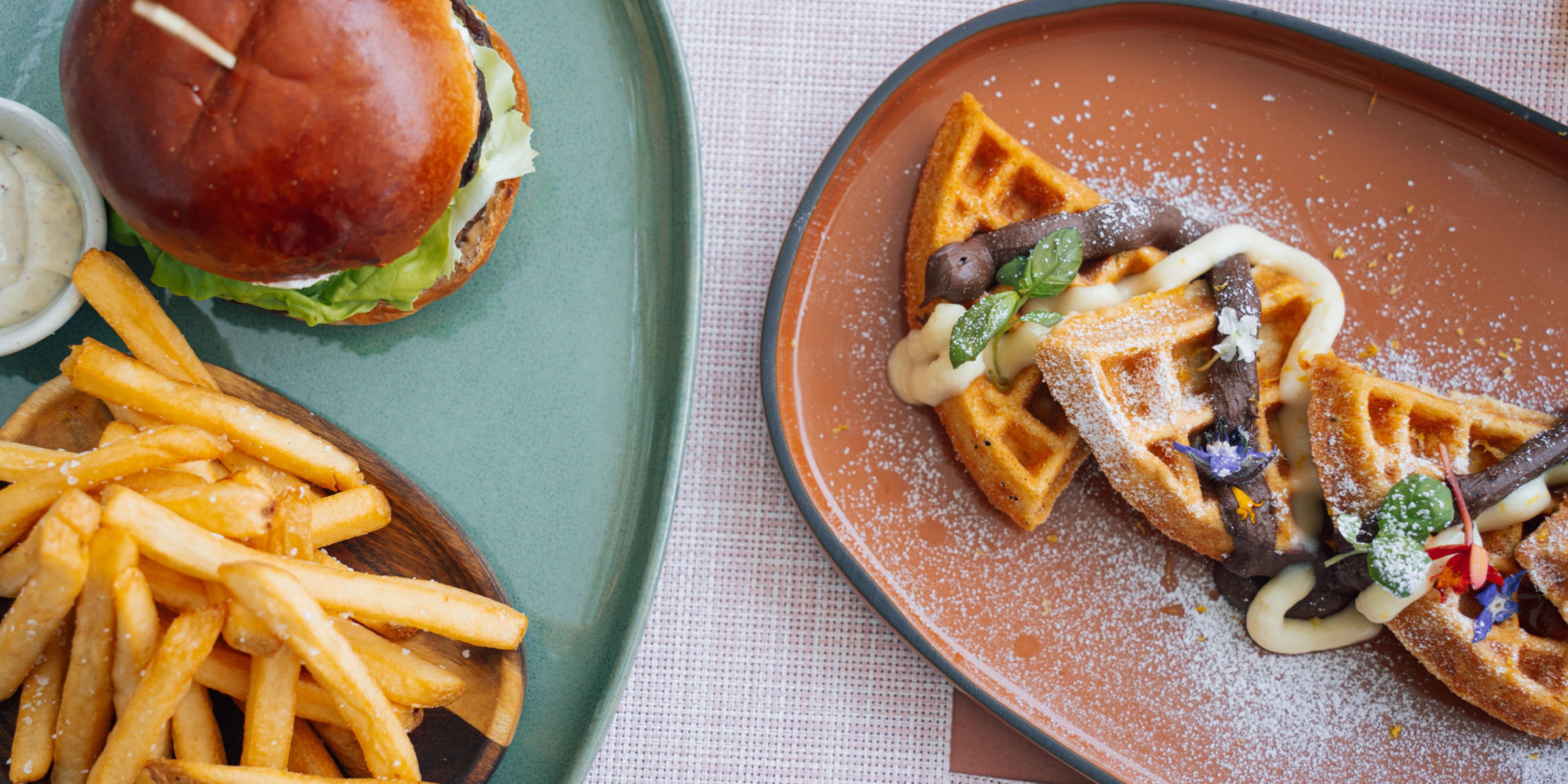 Burger and fries dish next to a waffles dish.
