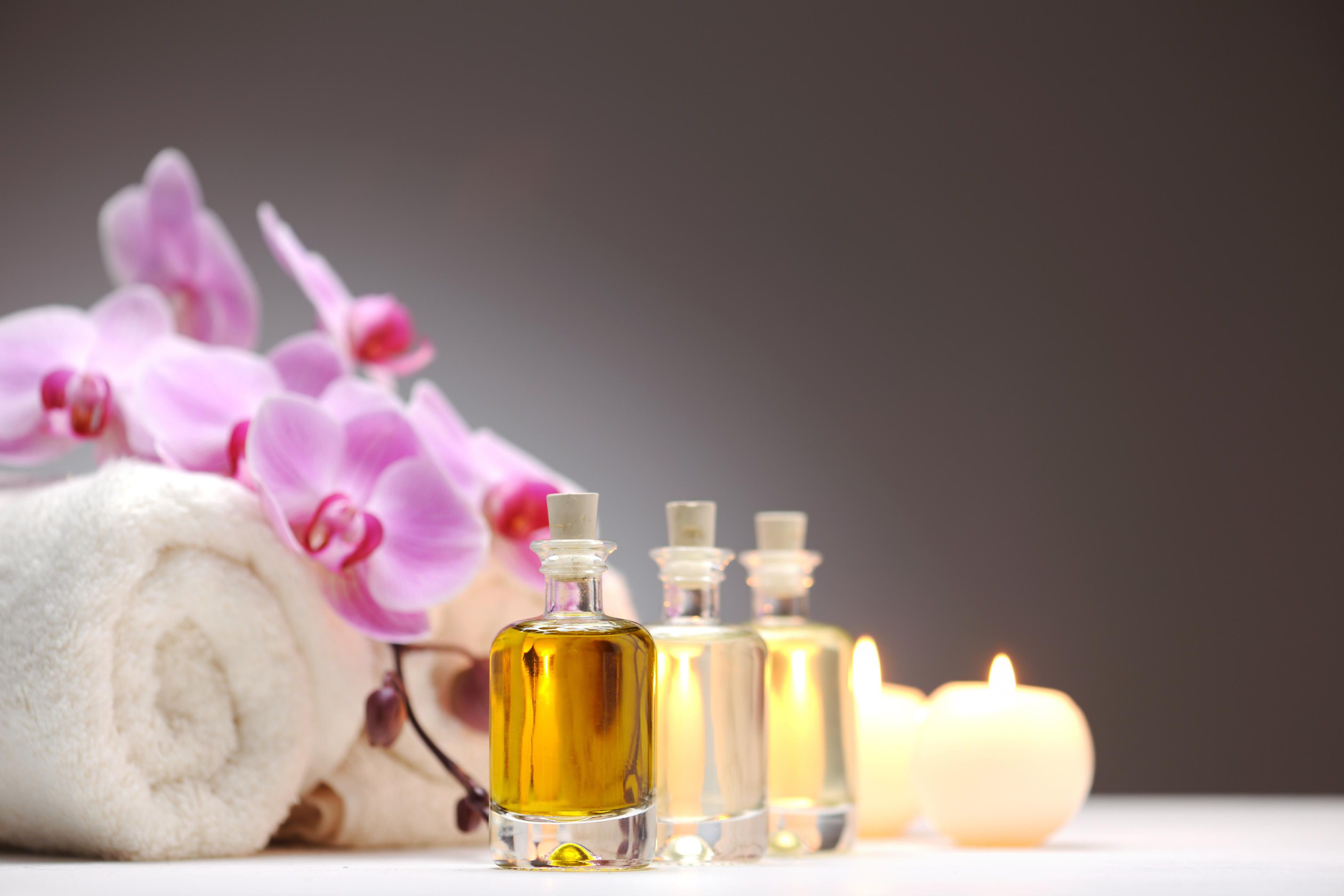 Spa essentials with a rolled towel, bath salts, orchids, and a small bottle.