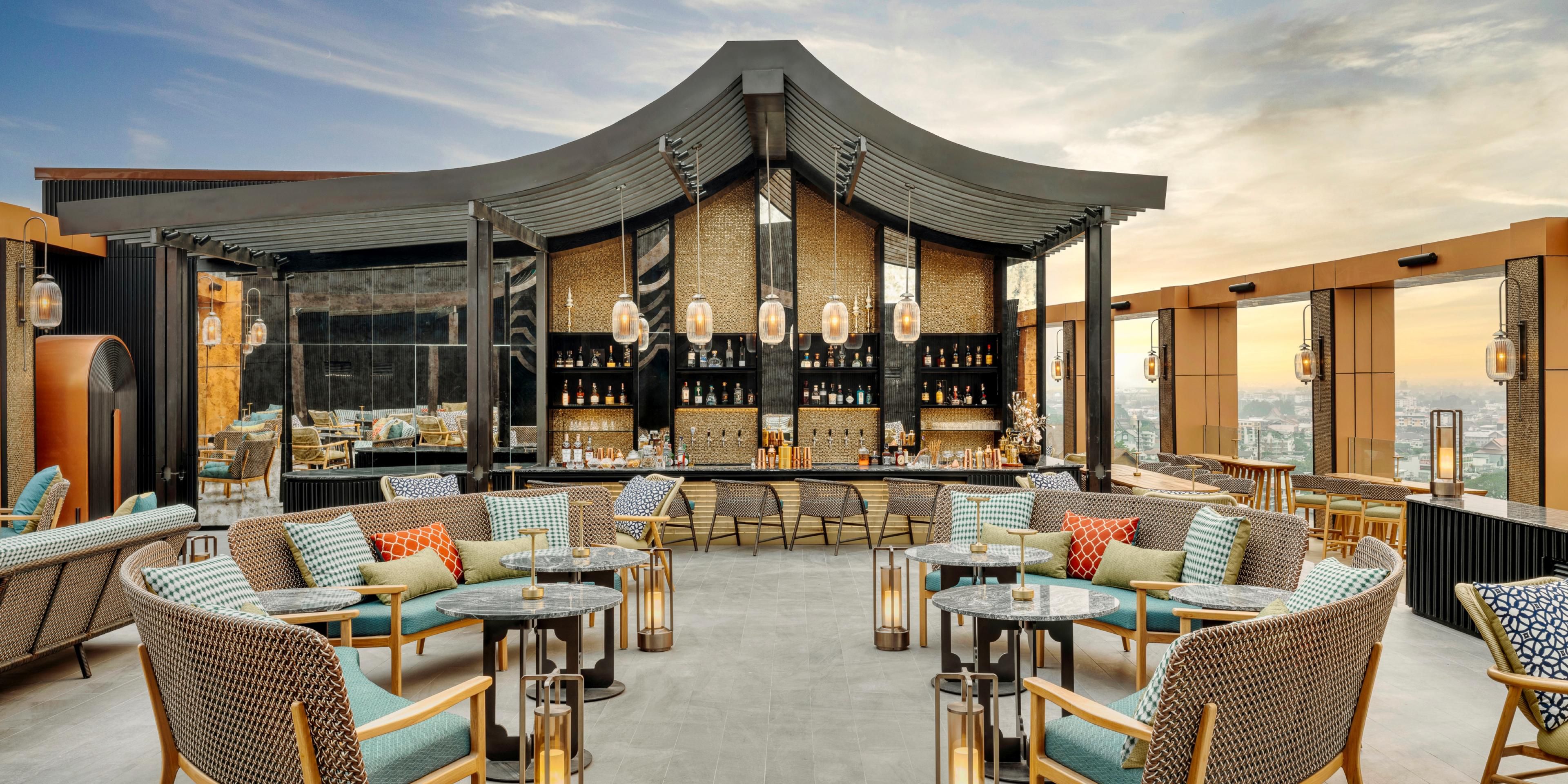 At the Sky Bar, where above us is only the sky, there is the exotic pleasure of watching a magical transformation as the sun sets in a blaze of red and gold, and the lights come on in the city far below.