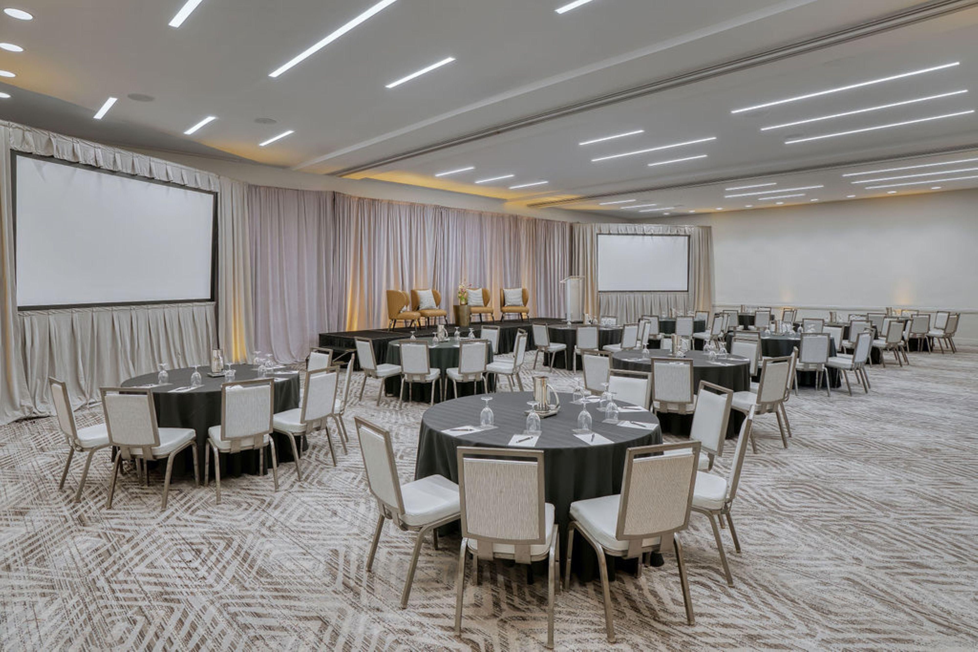 Meeting room with round tables and screens set up for conference.