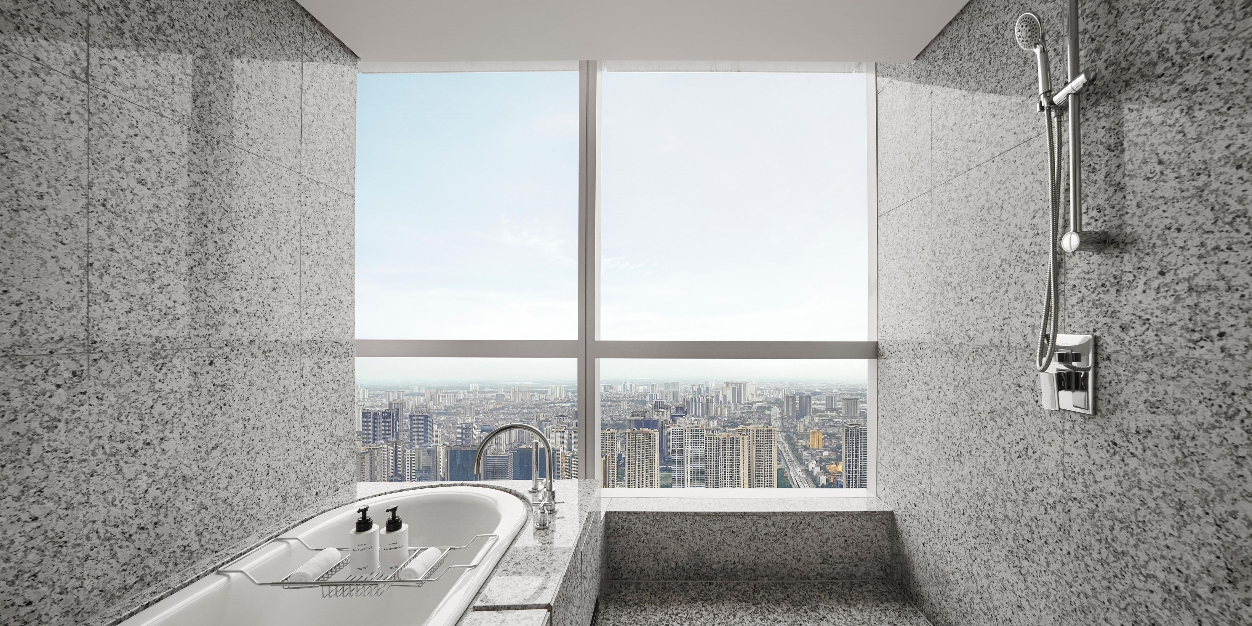 Spacious bathroom featuring bathtub, rain shower and a city view