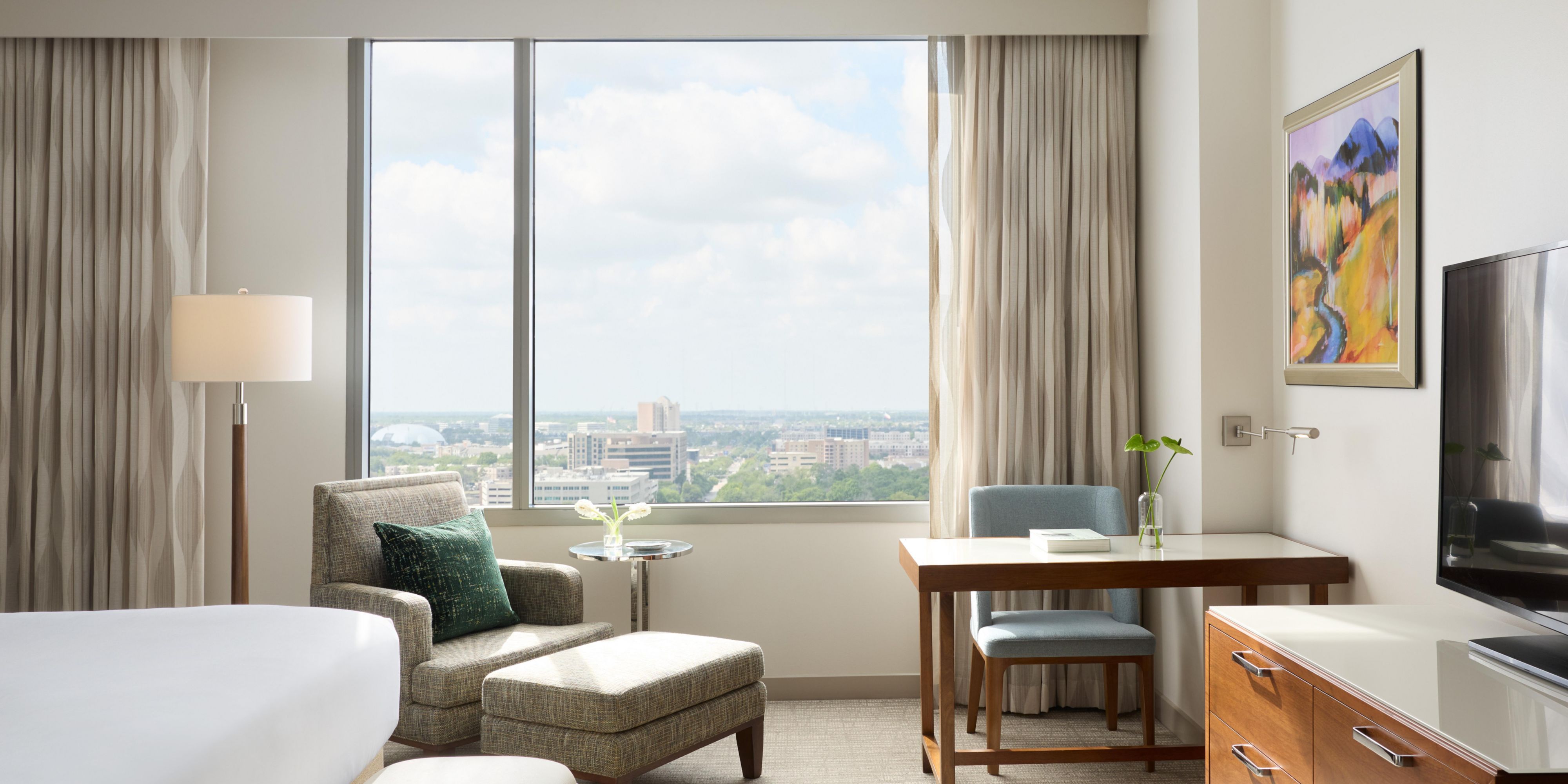Guest room with bed, desk, and city view.