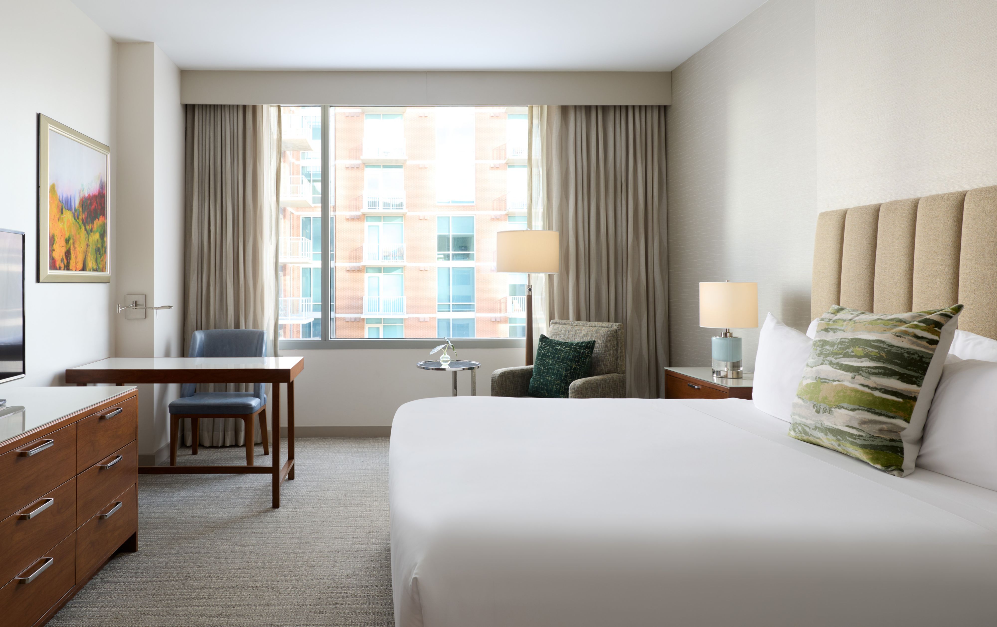 Hotel guest room with bed, desk, and large window view.