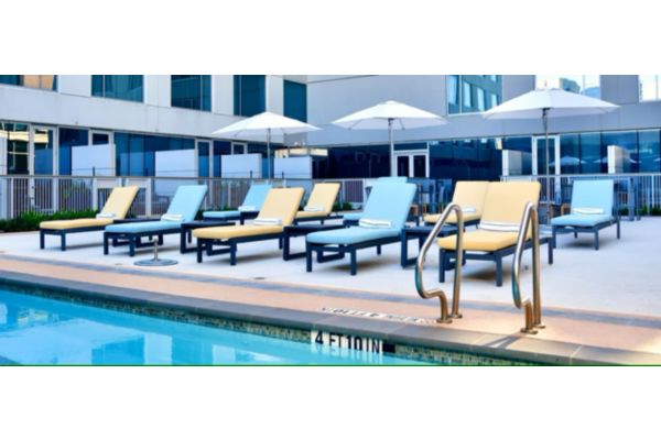 Pool deck with lounge chairs and umbrellas beside outdoor pool.