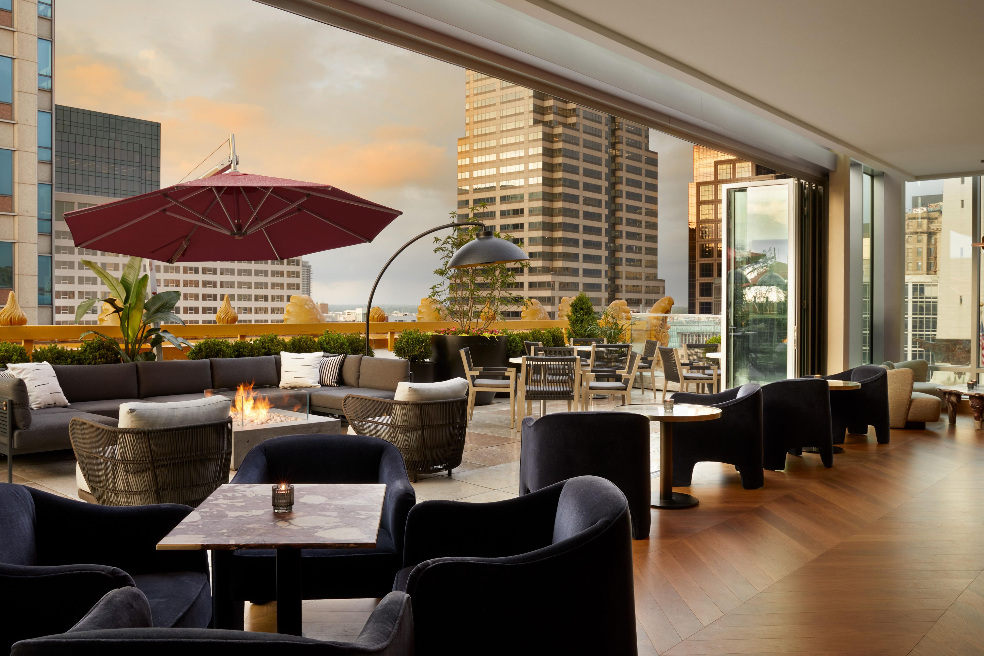Astrea Rooftop Bar indoor and outdoor seating with tables, couches, and firepits.