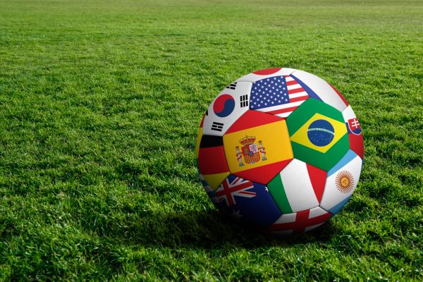 Soccer ball decorated with international flags on green grass