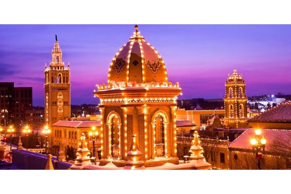 Illuminated Spanish-inspired towers and dome at dusk against a purple sky