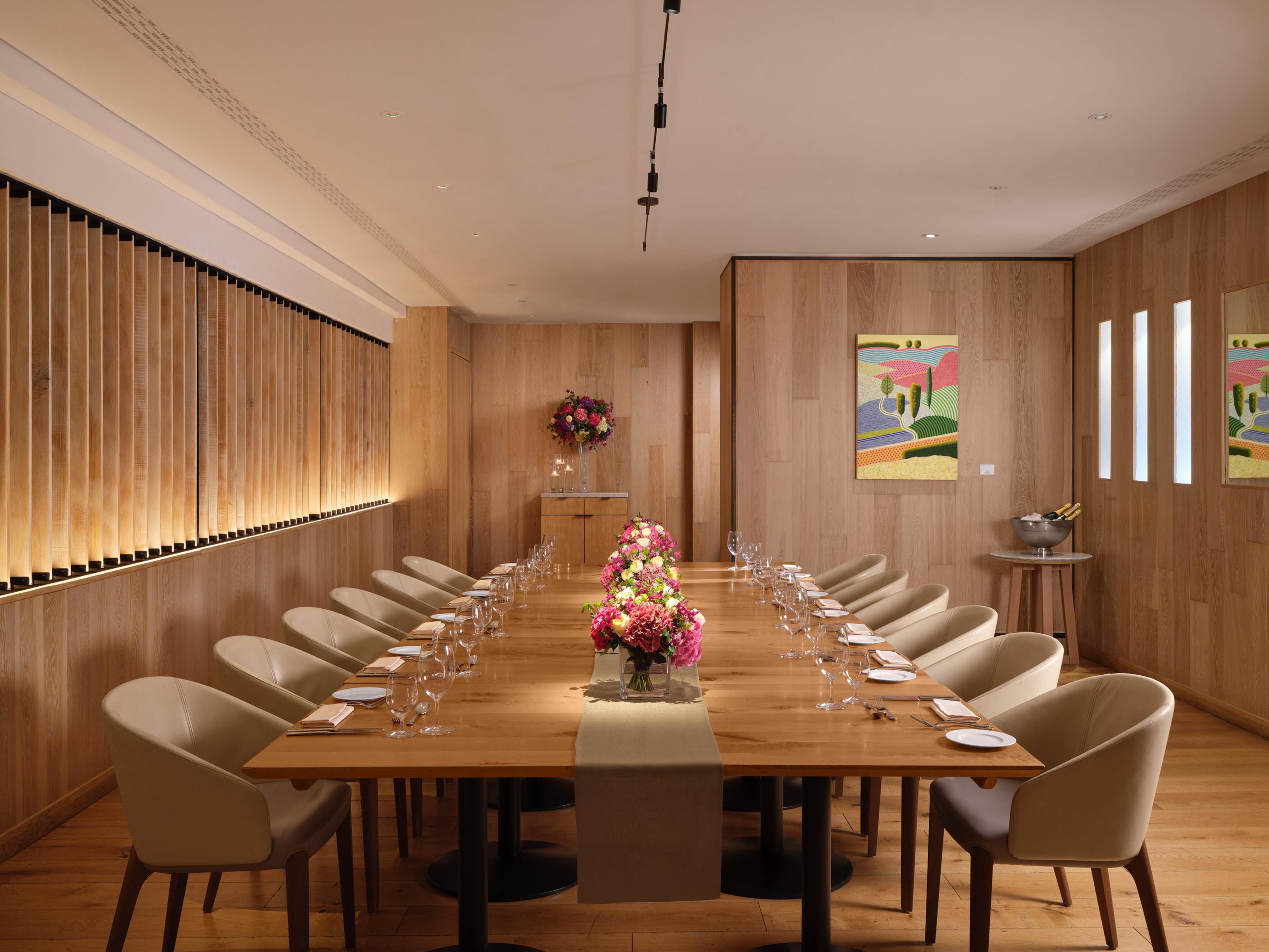 Private dining room with large table, pink decorative flowers, and wooden interior