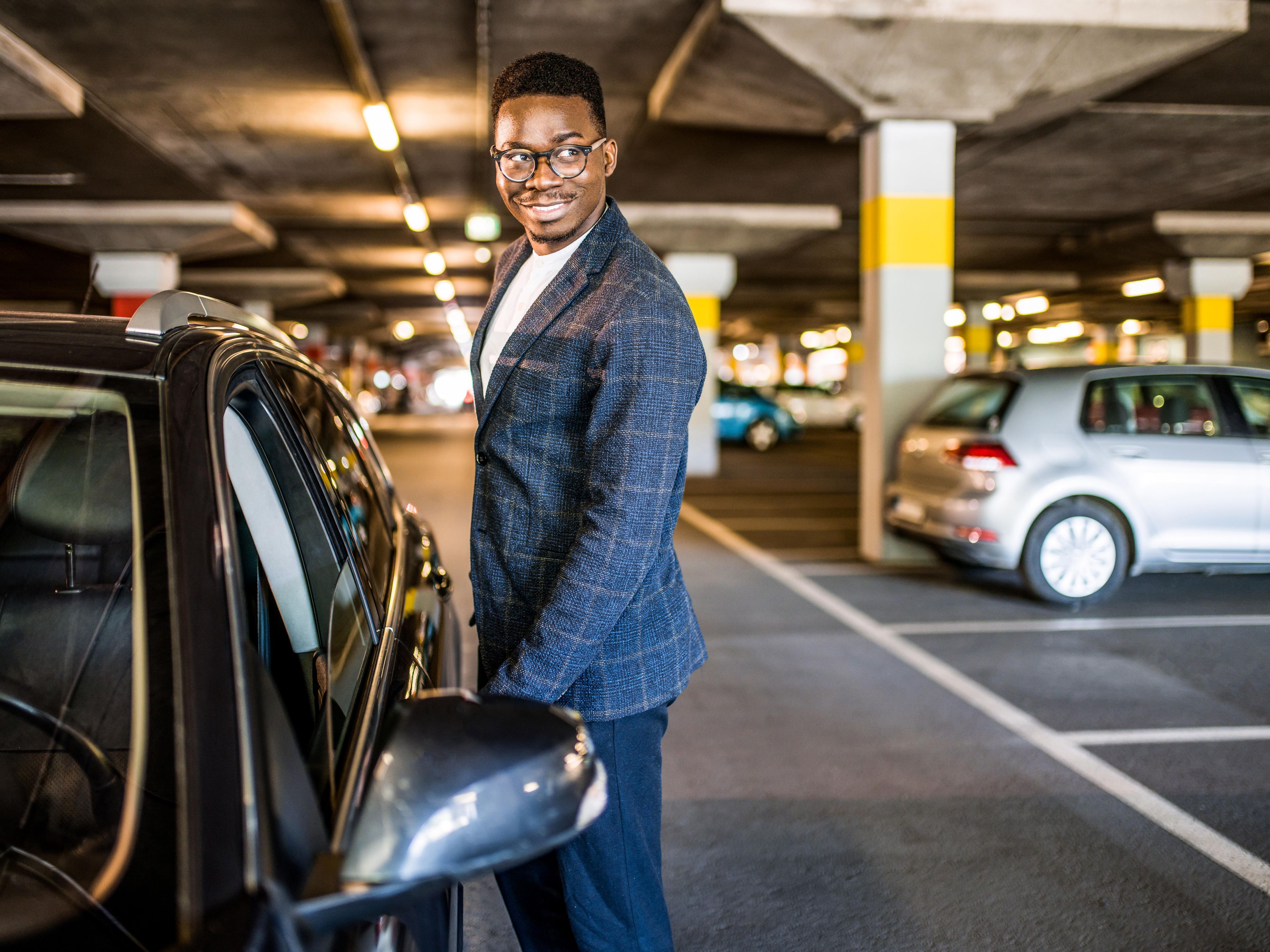 Man standing by his car in parking lot.