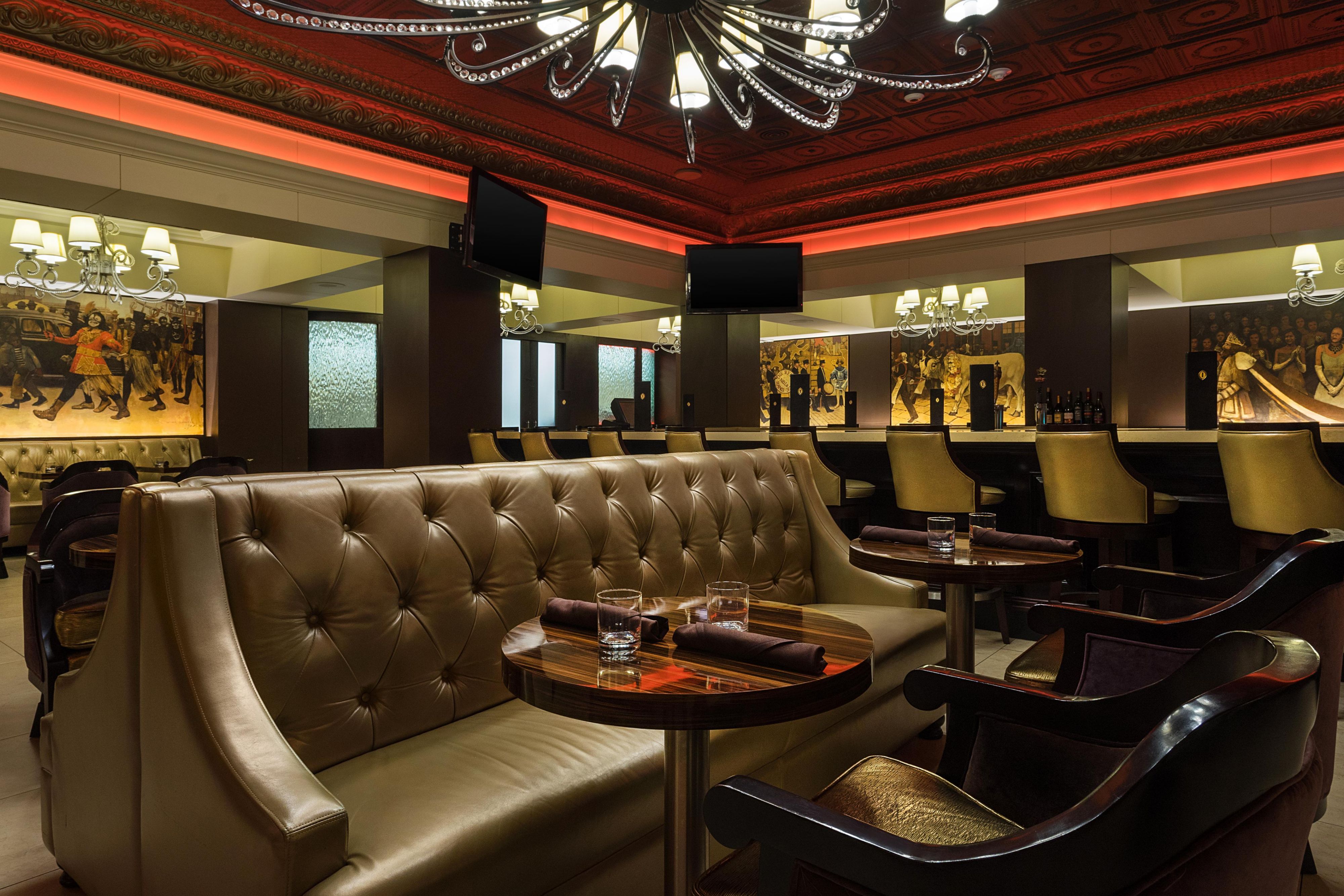 Upscale lounge with tufted banquette seating, cocktail tables, and warm lighting