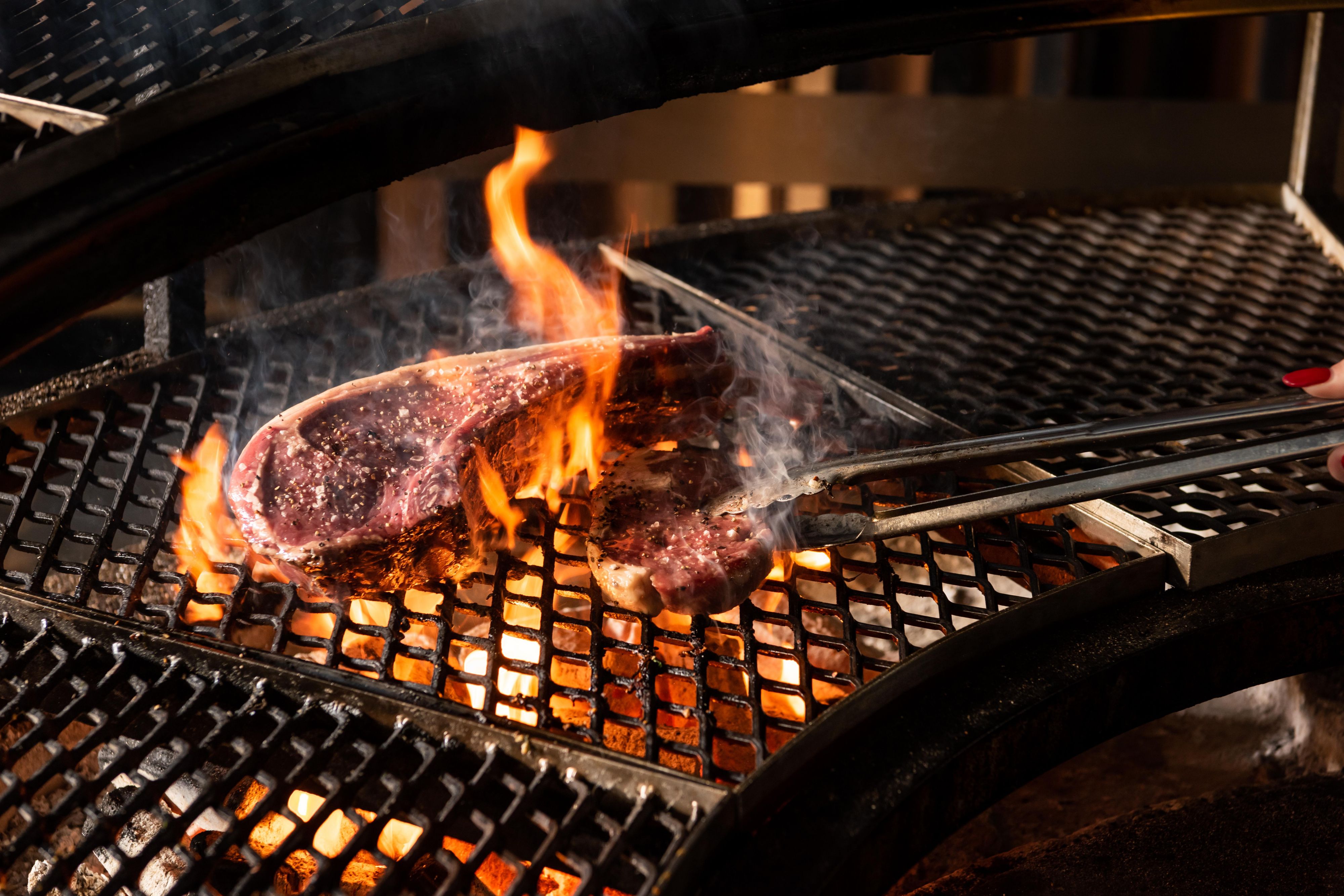 Steak being grilled on open fire grill.
