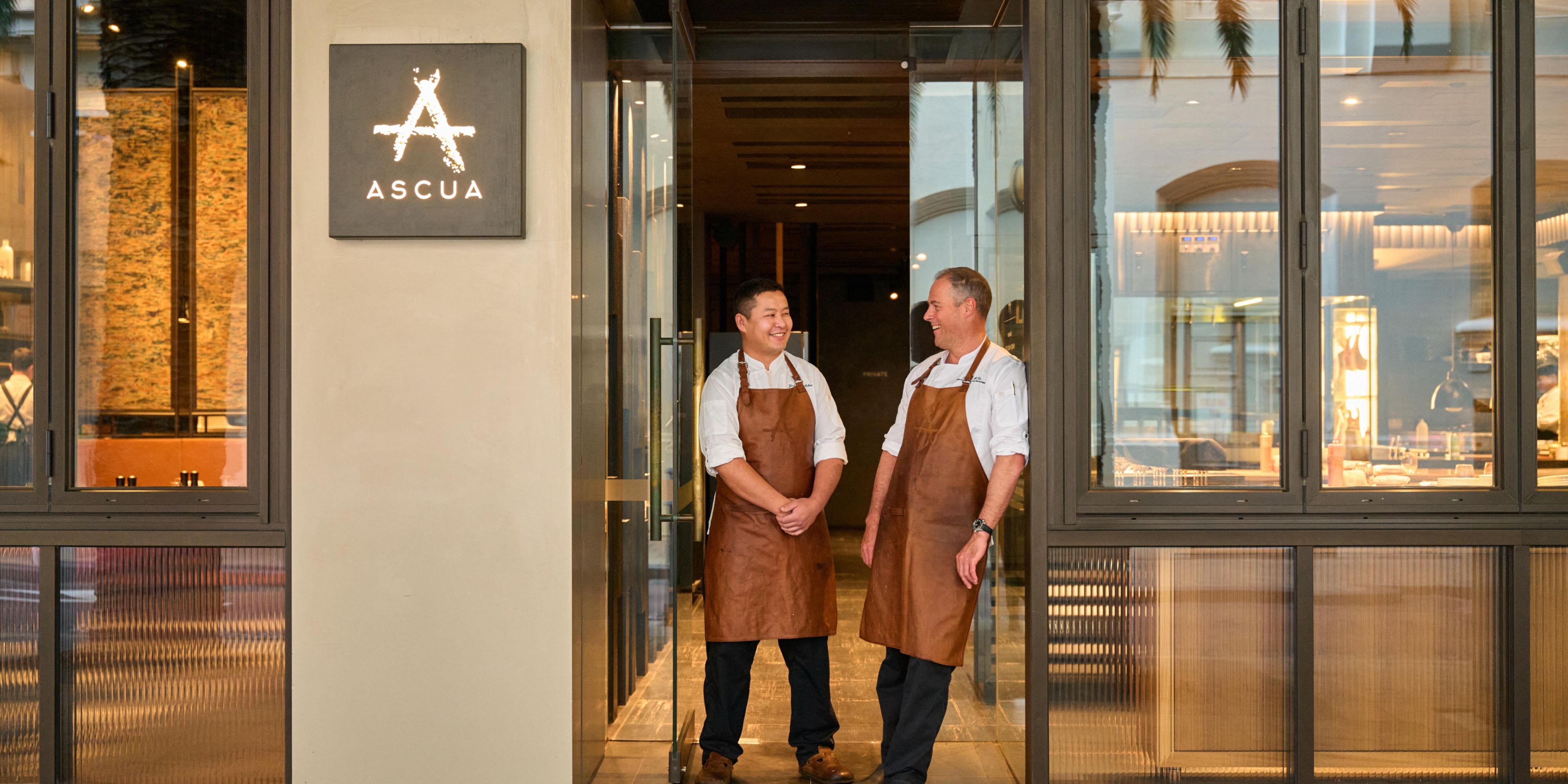Two servers standing in the door of Ascua.