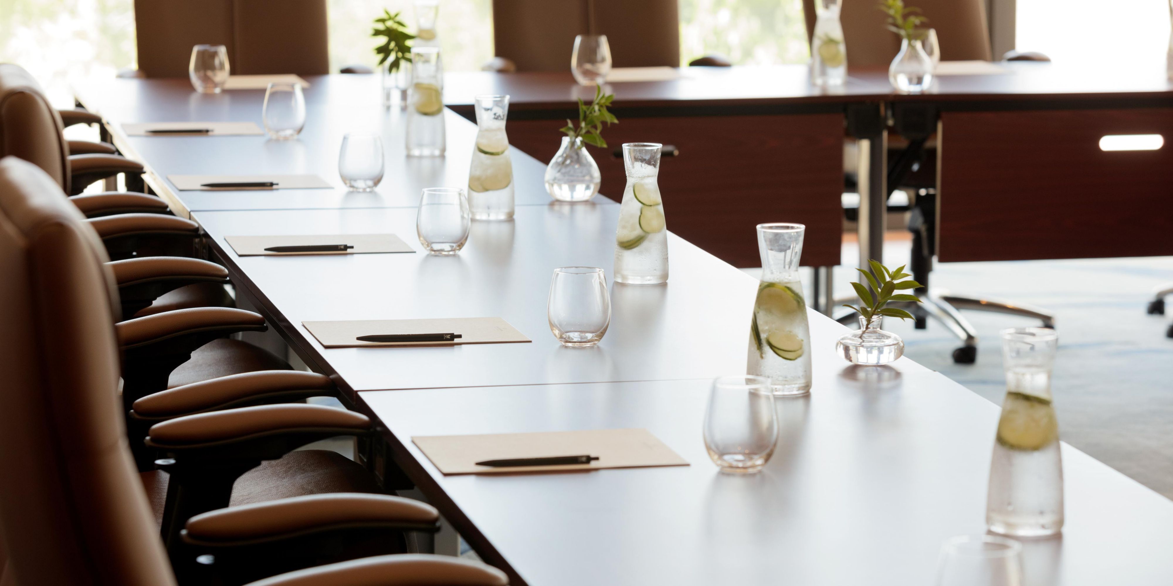 boardroom table set up with water, paper and pens