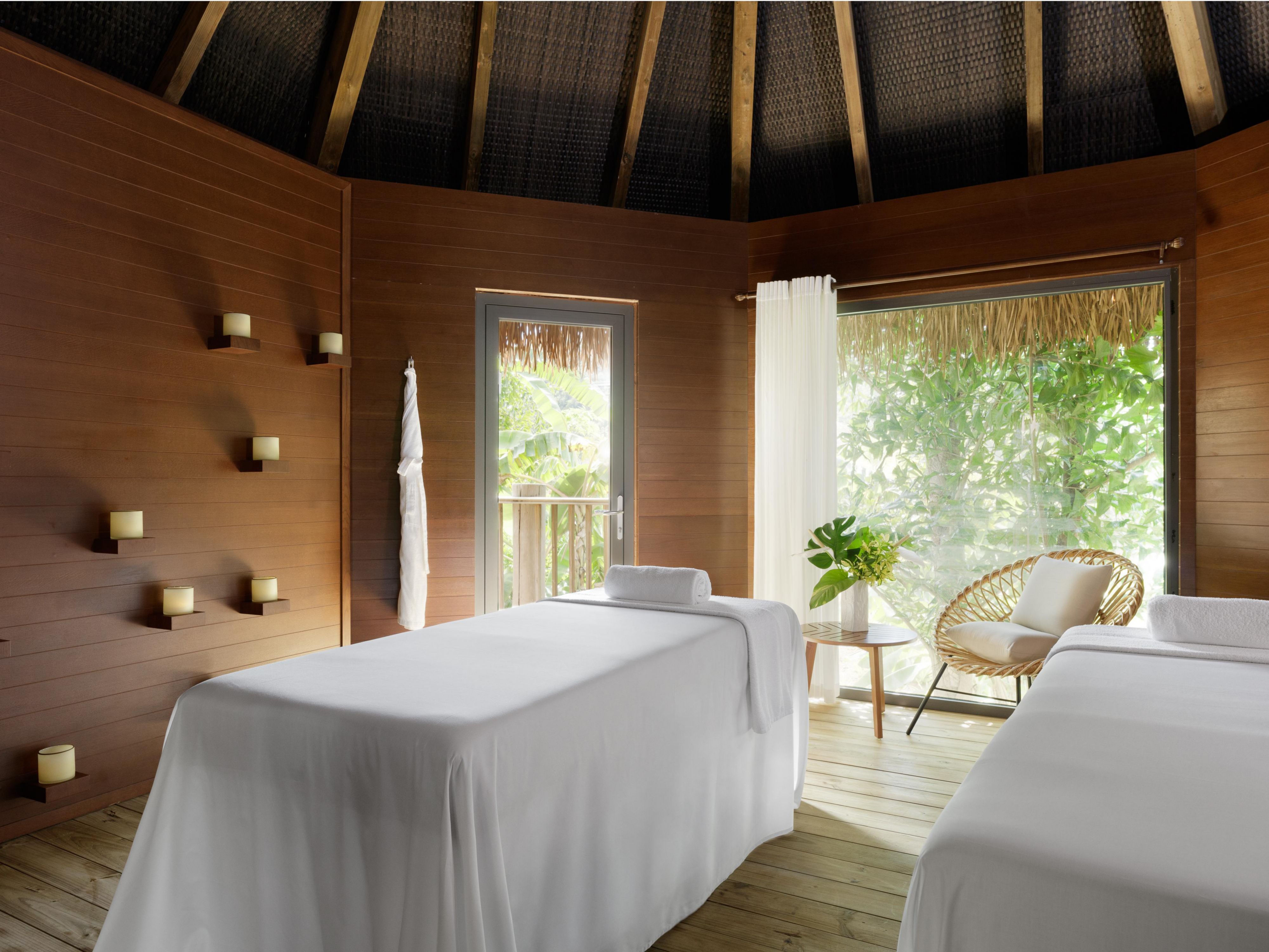 Two massage tables in a room with candles